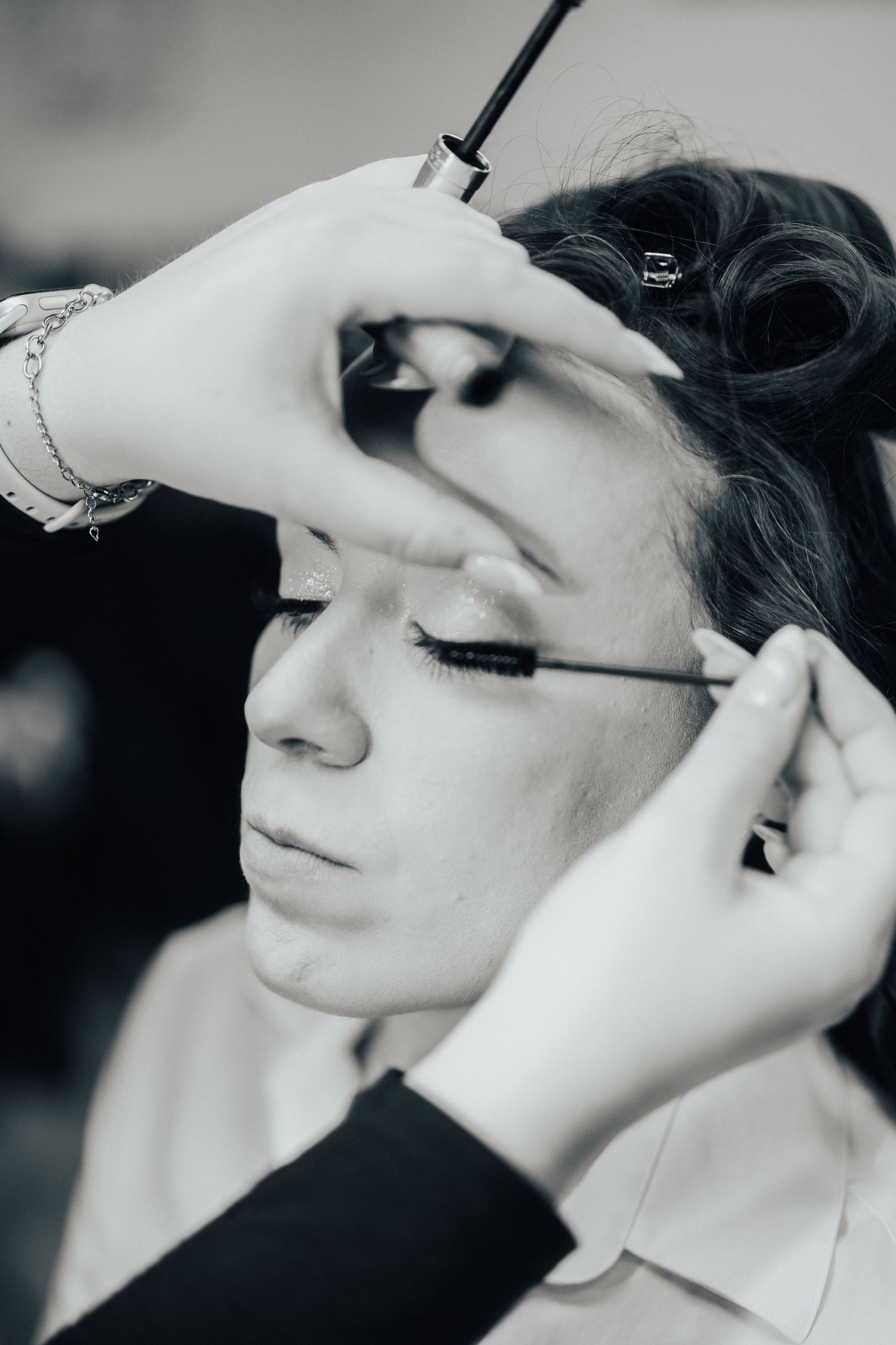 Makeup artist applying mascara during a professional beauty session in black and white photography.
