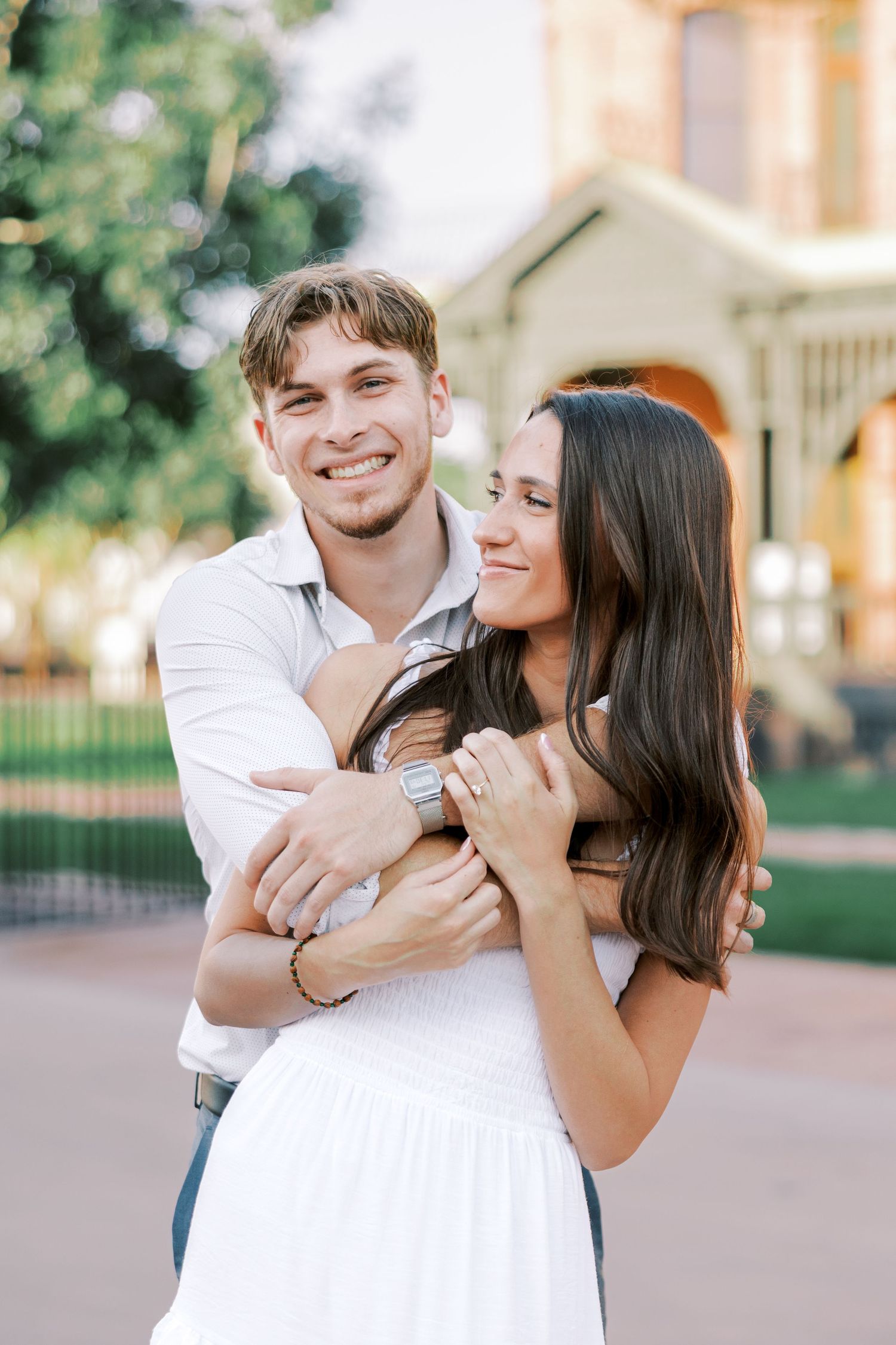 A joyful couple shares intimate moments during their outdoor engagement photoshoot.