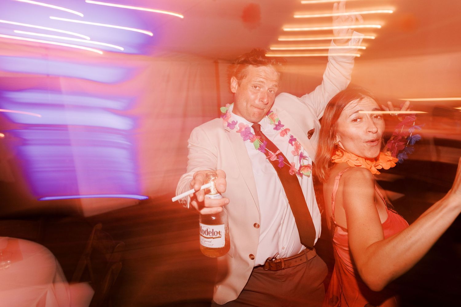 Party guests dancing in motion blur with colorful lighting effects.