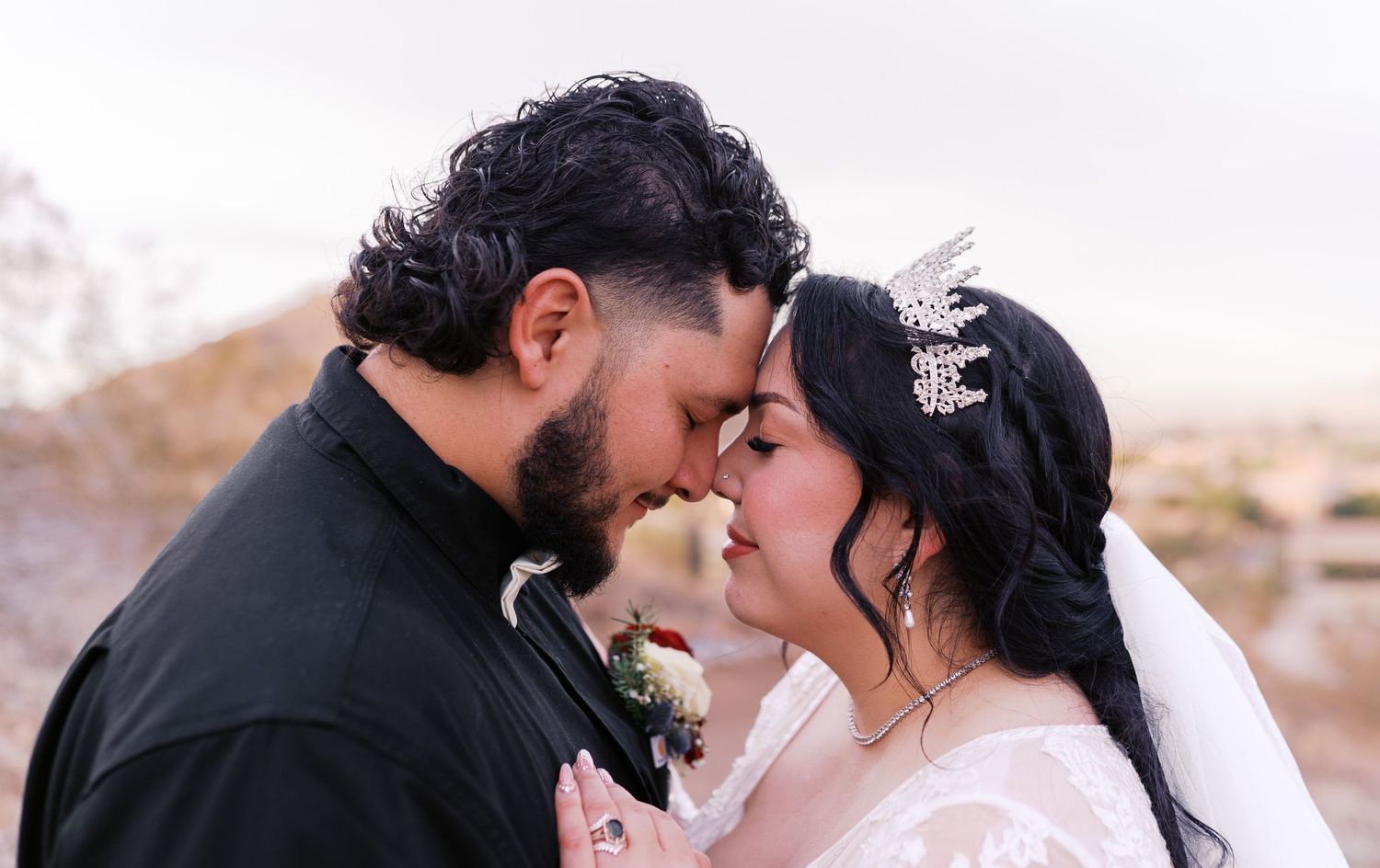 A romantic close-up of a couple celebrating their wedding day in a desert landscape under soft lighting.