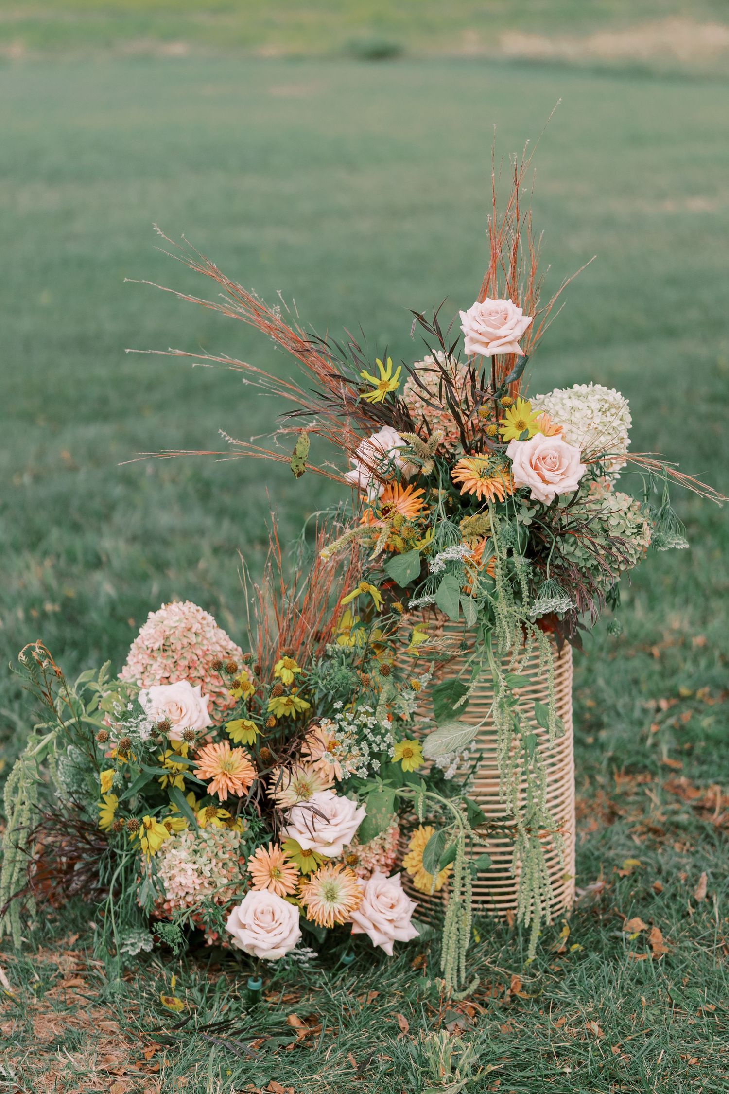 Beautiful floral arrangements with pink roses and orange gerberas set on grassy ground.