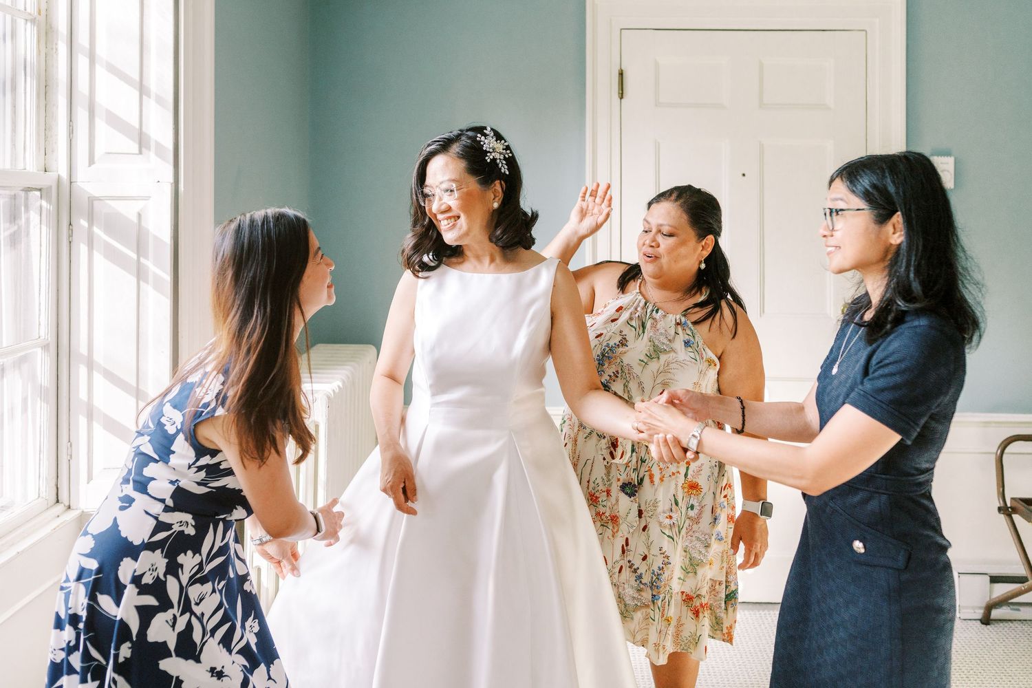 A group enjoys a fun moment with raised hands in an indoor space with white walls and natural lighting.
