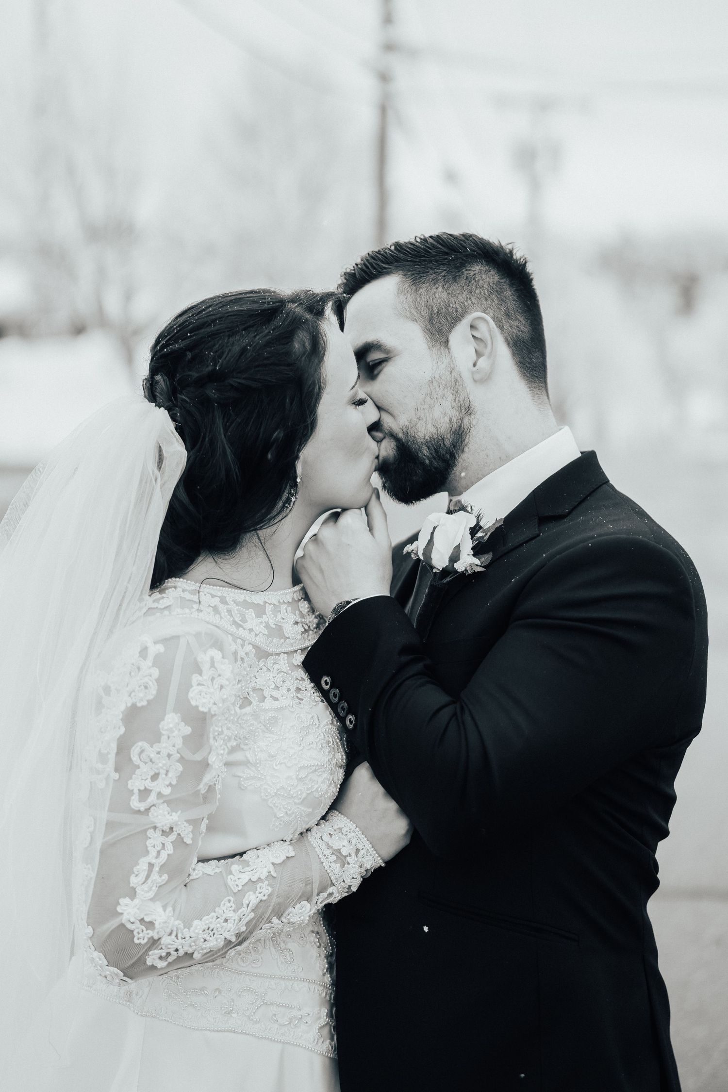 Intimate black and white portrait of newlyweds sharing a tender moment outdoors.