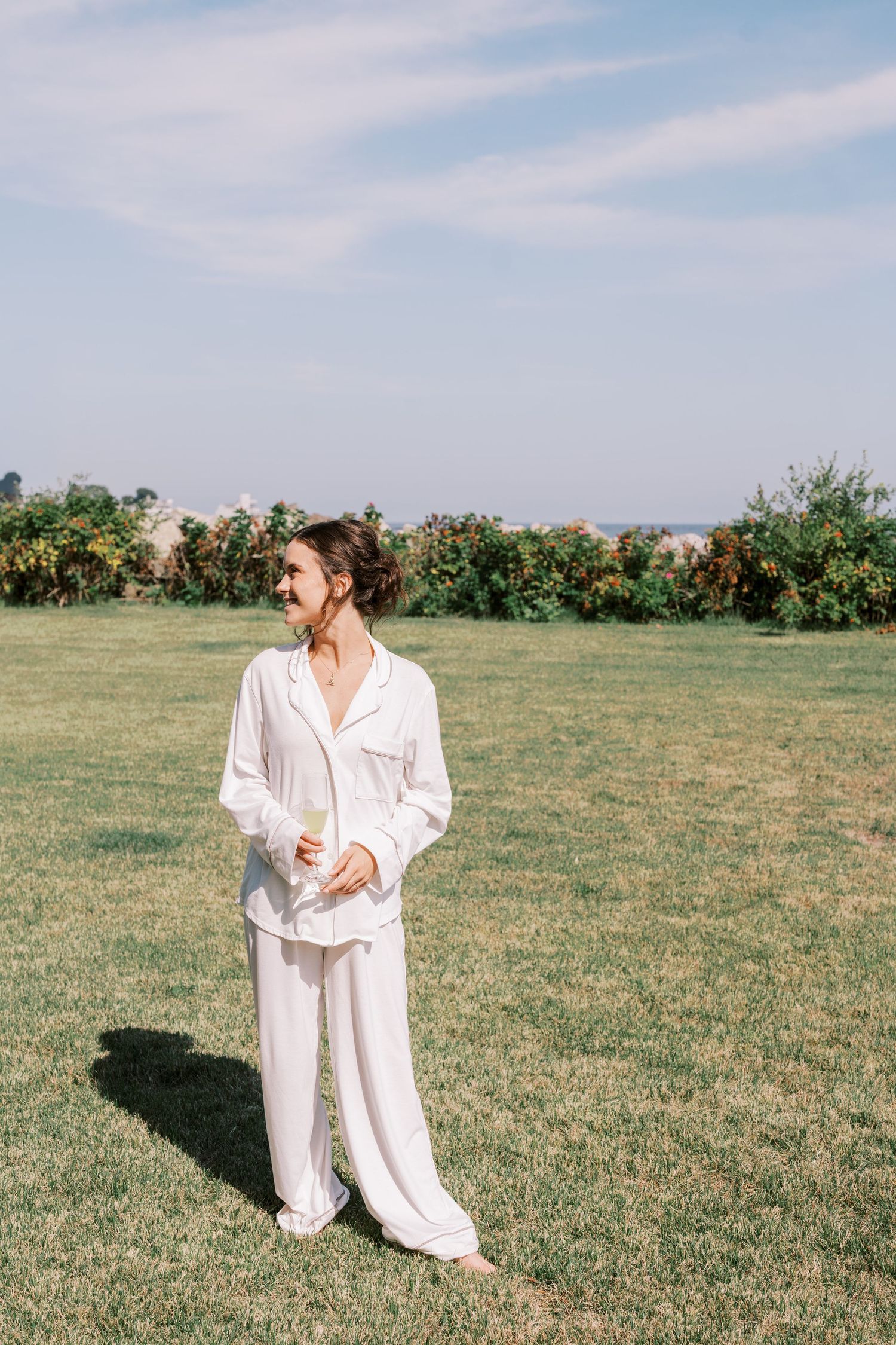 Person in flowing white outfit dances in open field on sunny day.