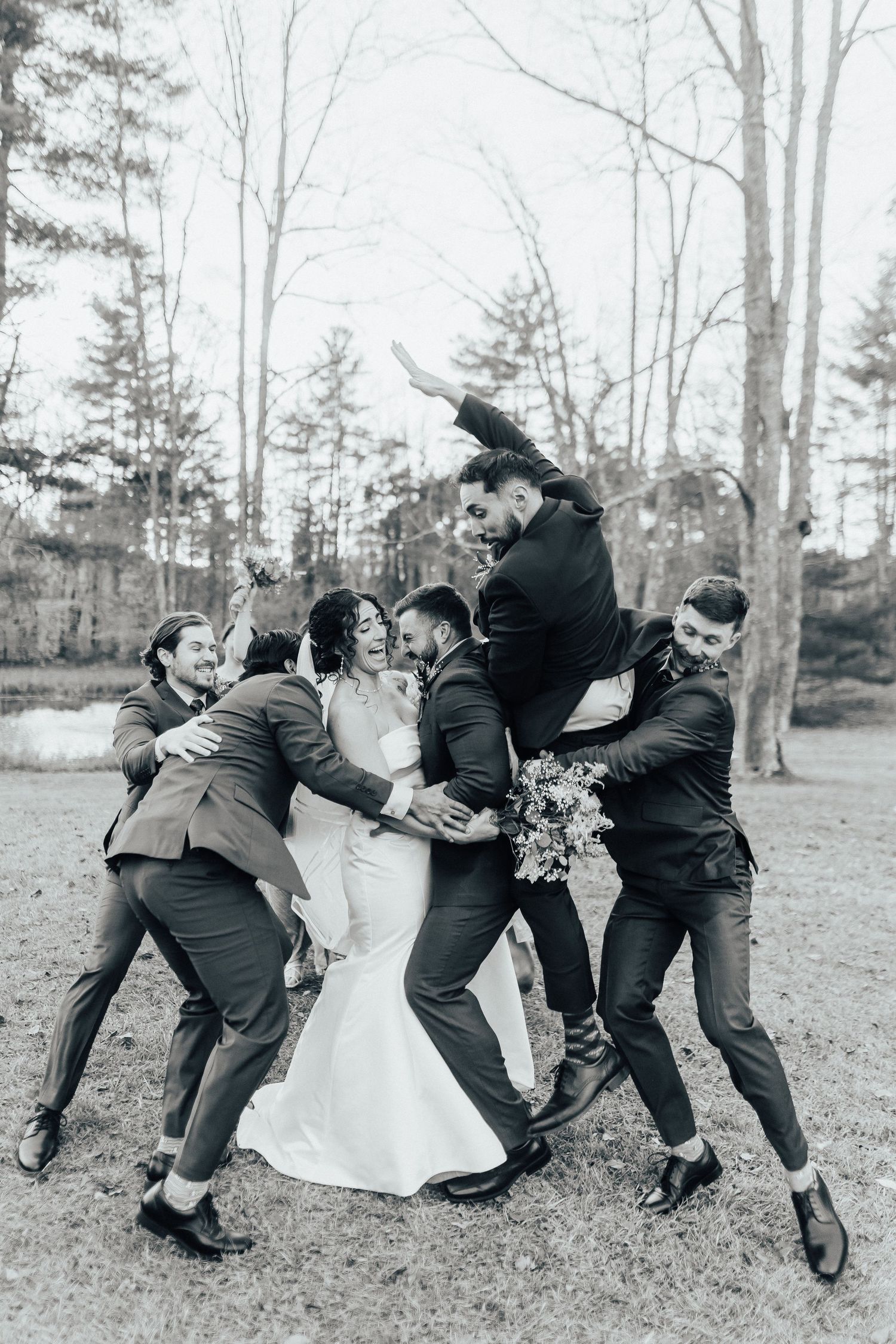 Black and white photo sequence showing wedding party playfully falling over like dominoes in an outdoor setting.