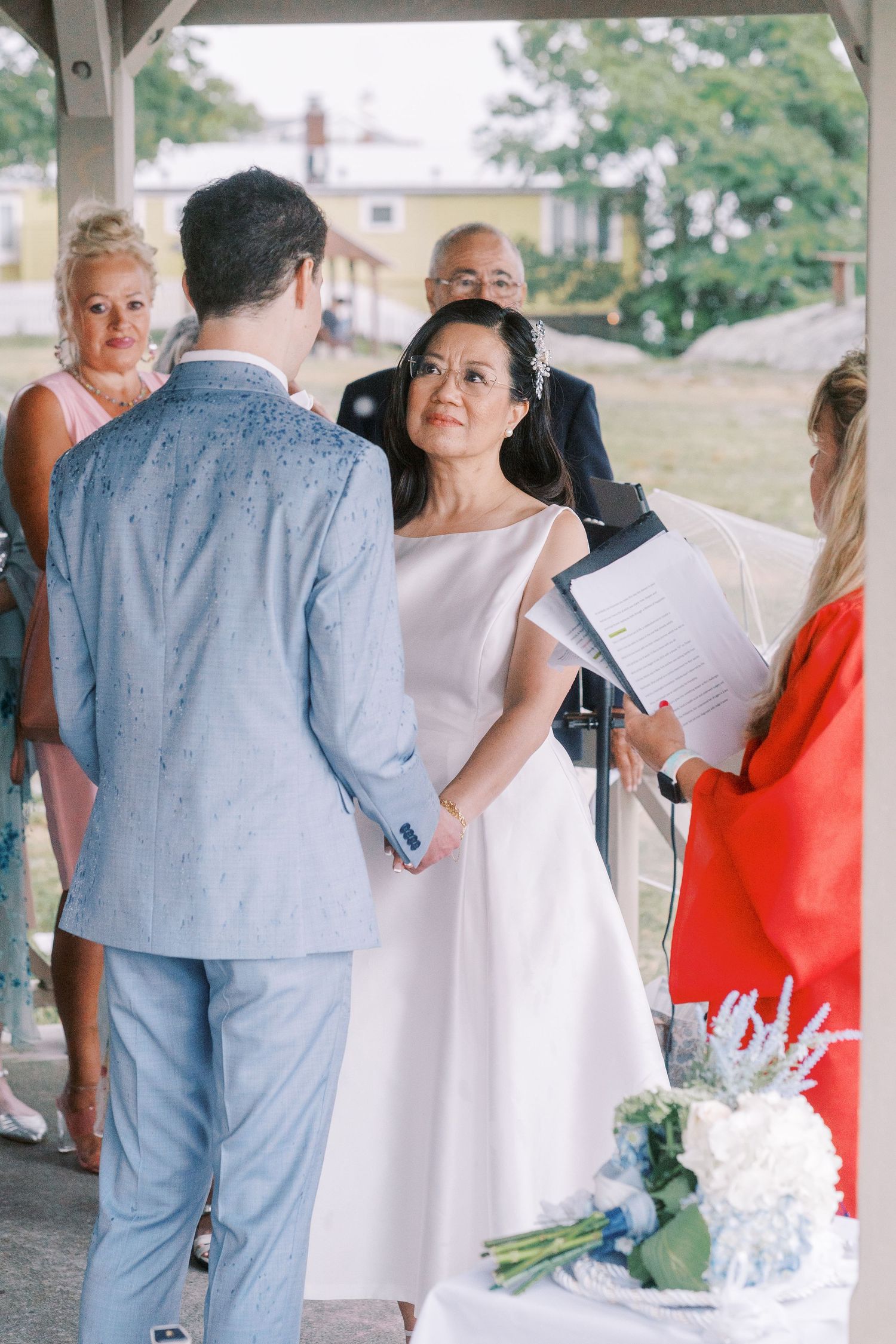 Wedding guests and couple mingling under covered outdoor area.