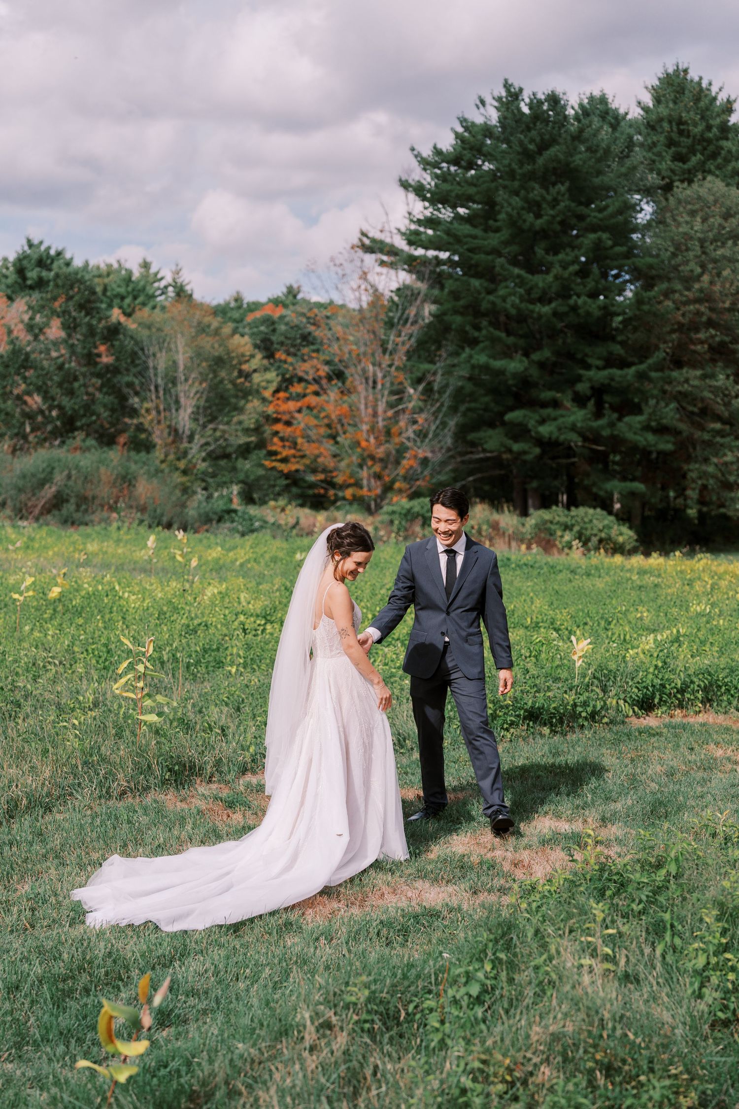 Couple walking through wildflower field in wedding attire.