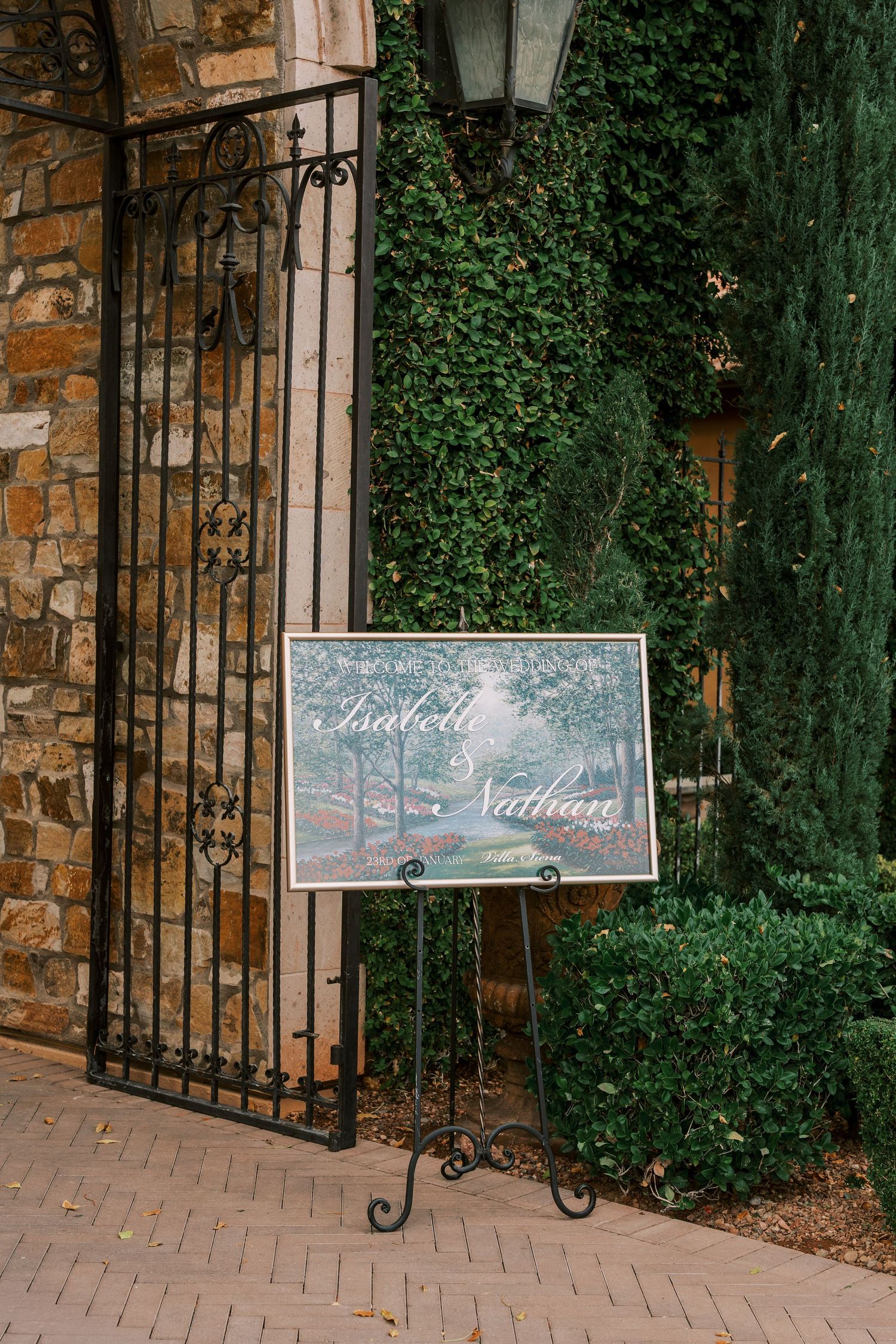 Elegant chalkboard wedding signs displayed on wrought iron stands against a stone wall with ivy backdrop.