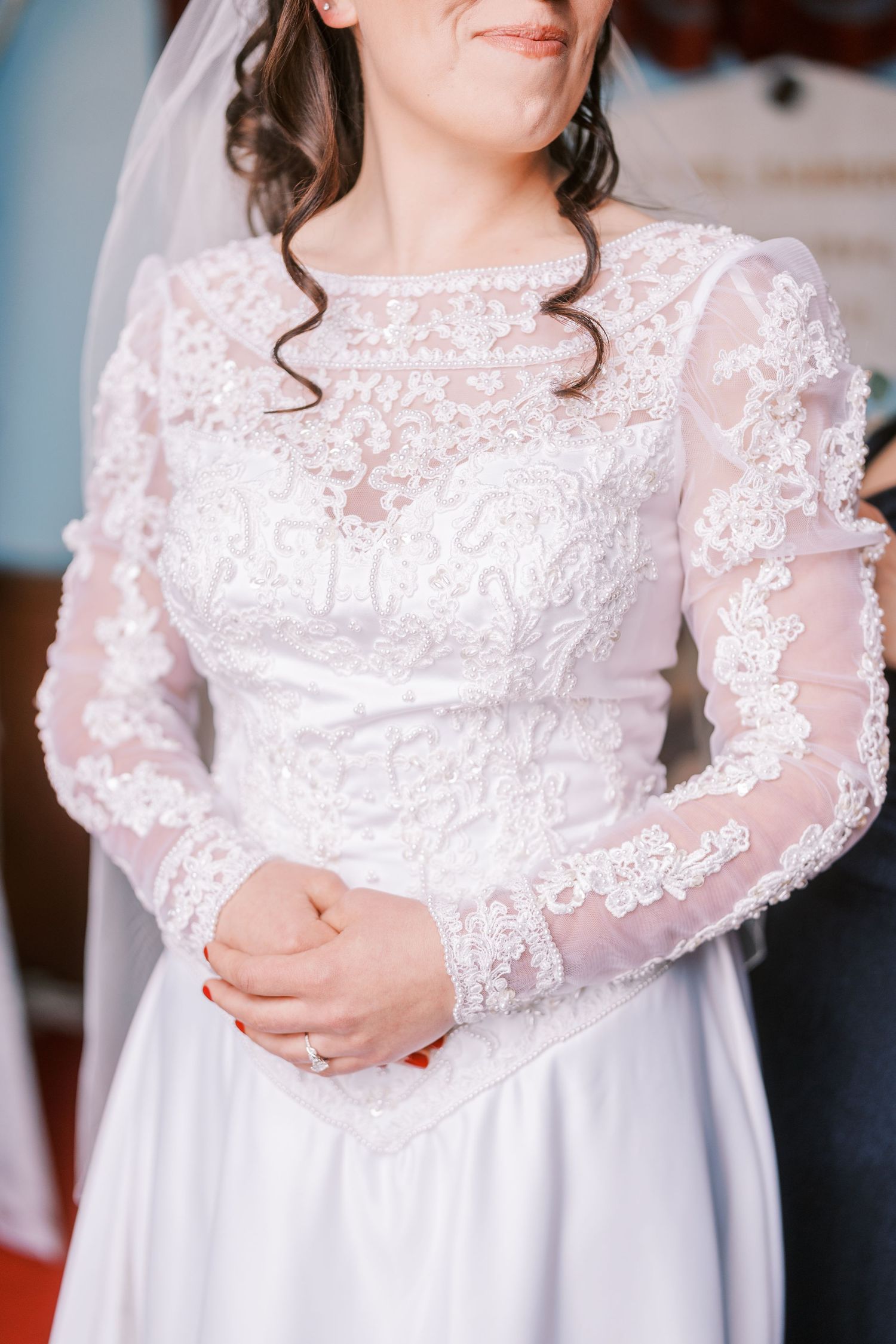 Close-up of delicate lace long sleeve wedding dress with intricate embroidery details.