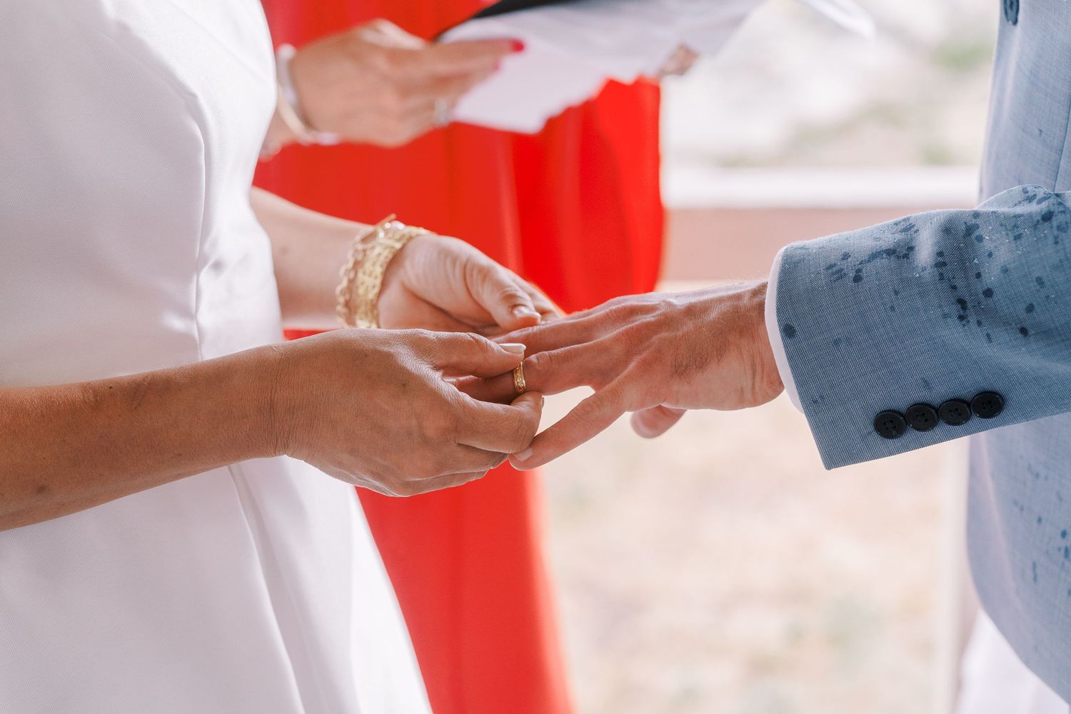 Close-up of hands exchanging rings during a wedding ceremony.