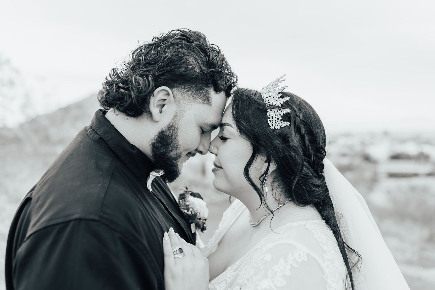 A tender moment between newlyweds in black and white as they share an intimate embrace outdoors.