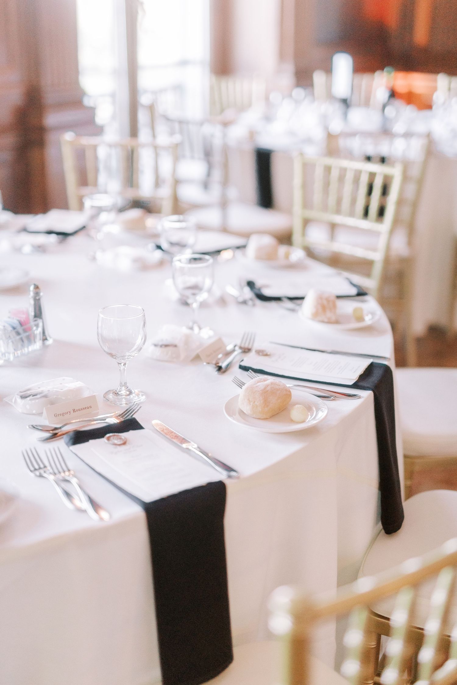 Elegant wedding reception tables set with white linens, black napkins, and crystal glasses.