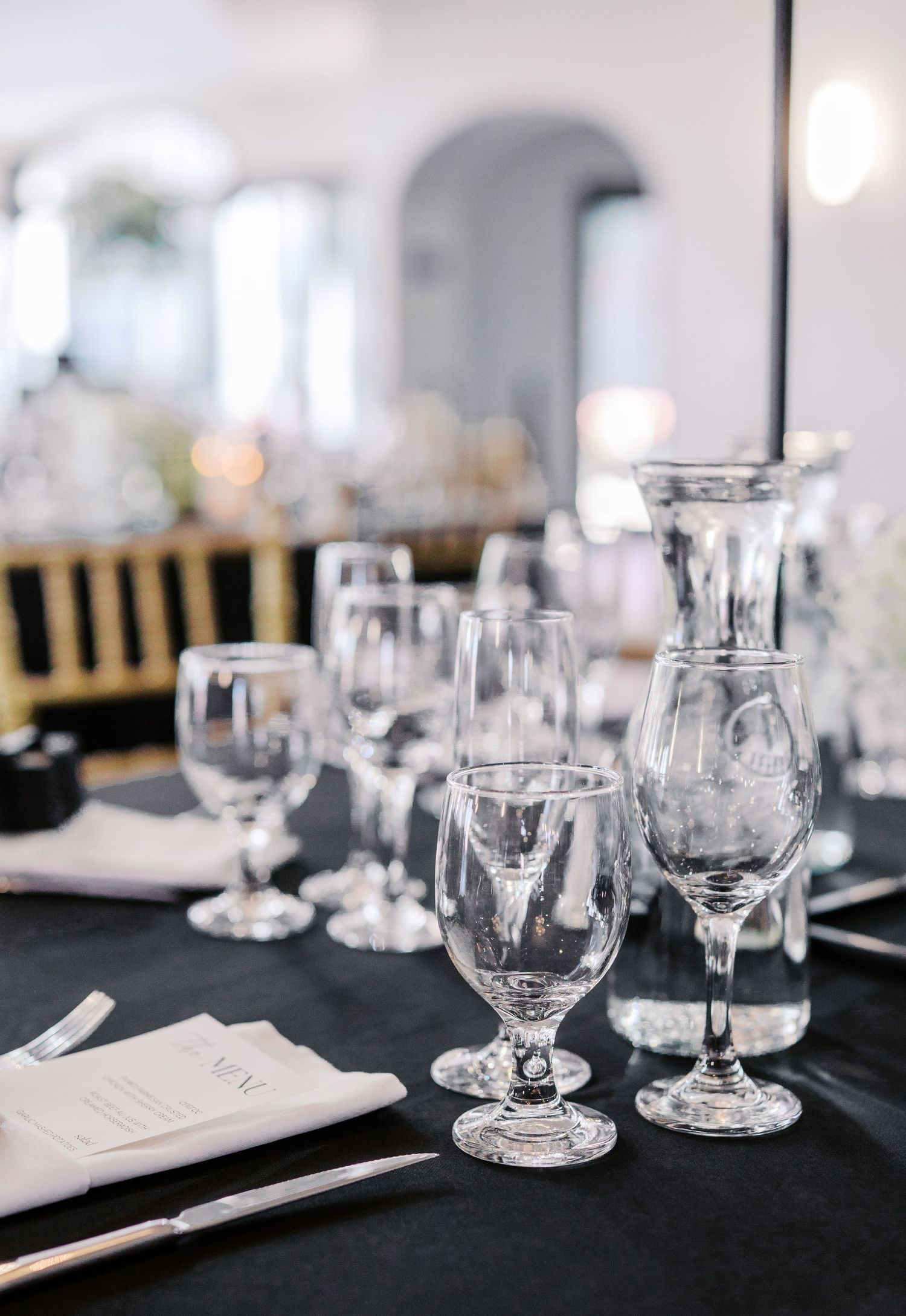 Elegant table settings with crystal wine glasses and black linens at a formal event.