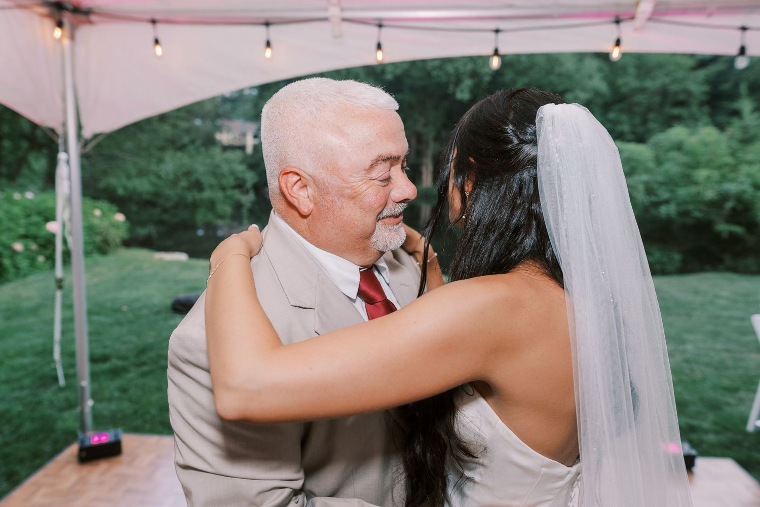 Outdoor wedding ceremony celebration under string lights with guests gathered.