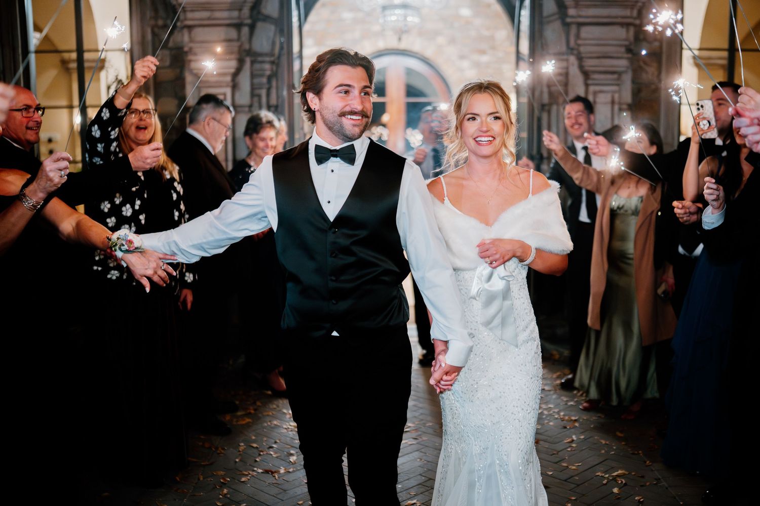 A joyful couple dances together during their first dance at an elegant indoor wedding reception.