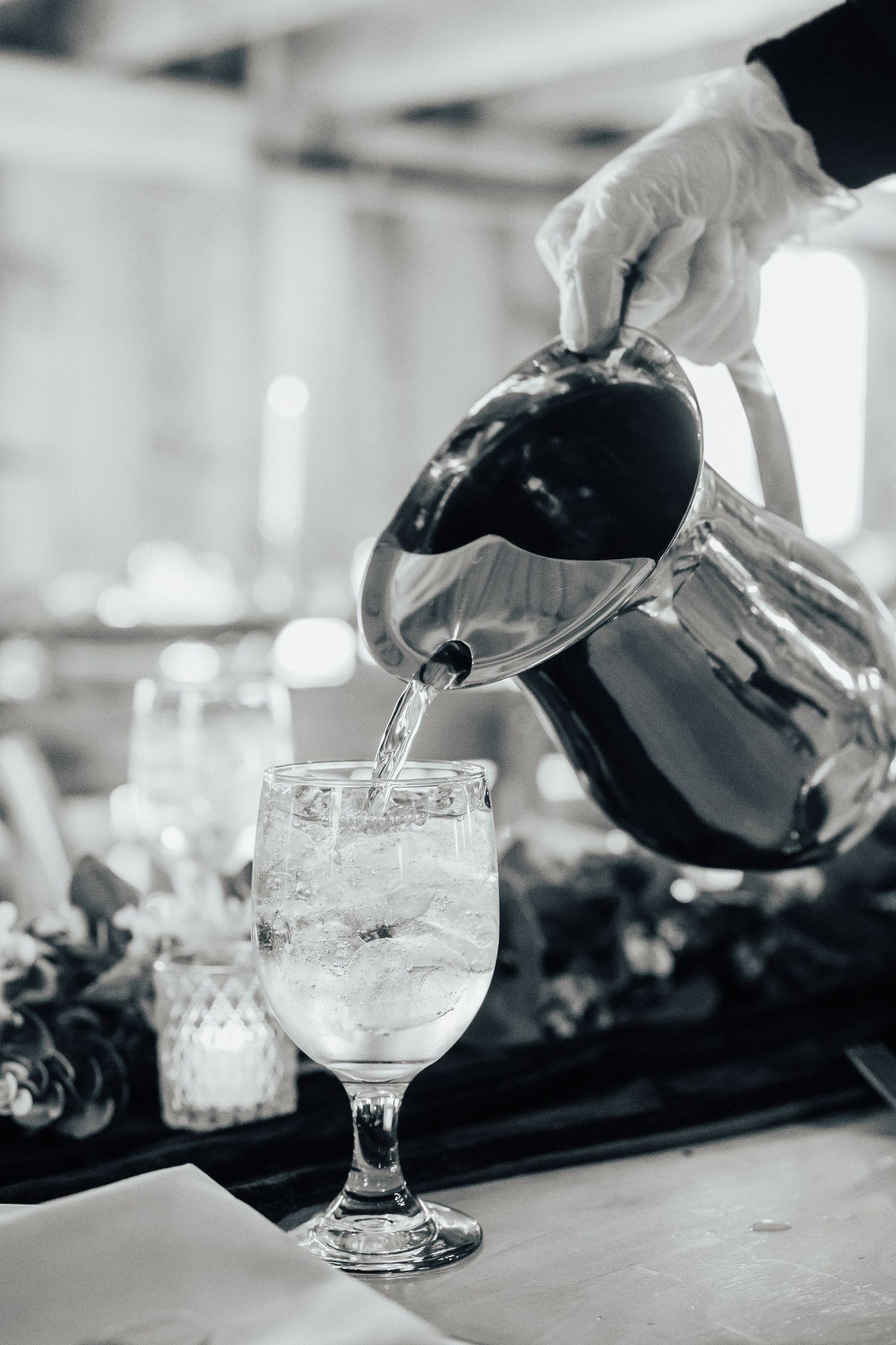 Black and white photo sequence showing bartender pouring a cocktail into a glass with precise technique.