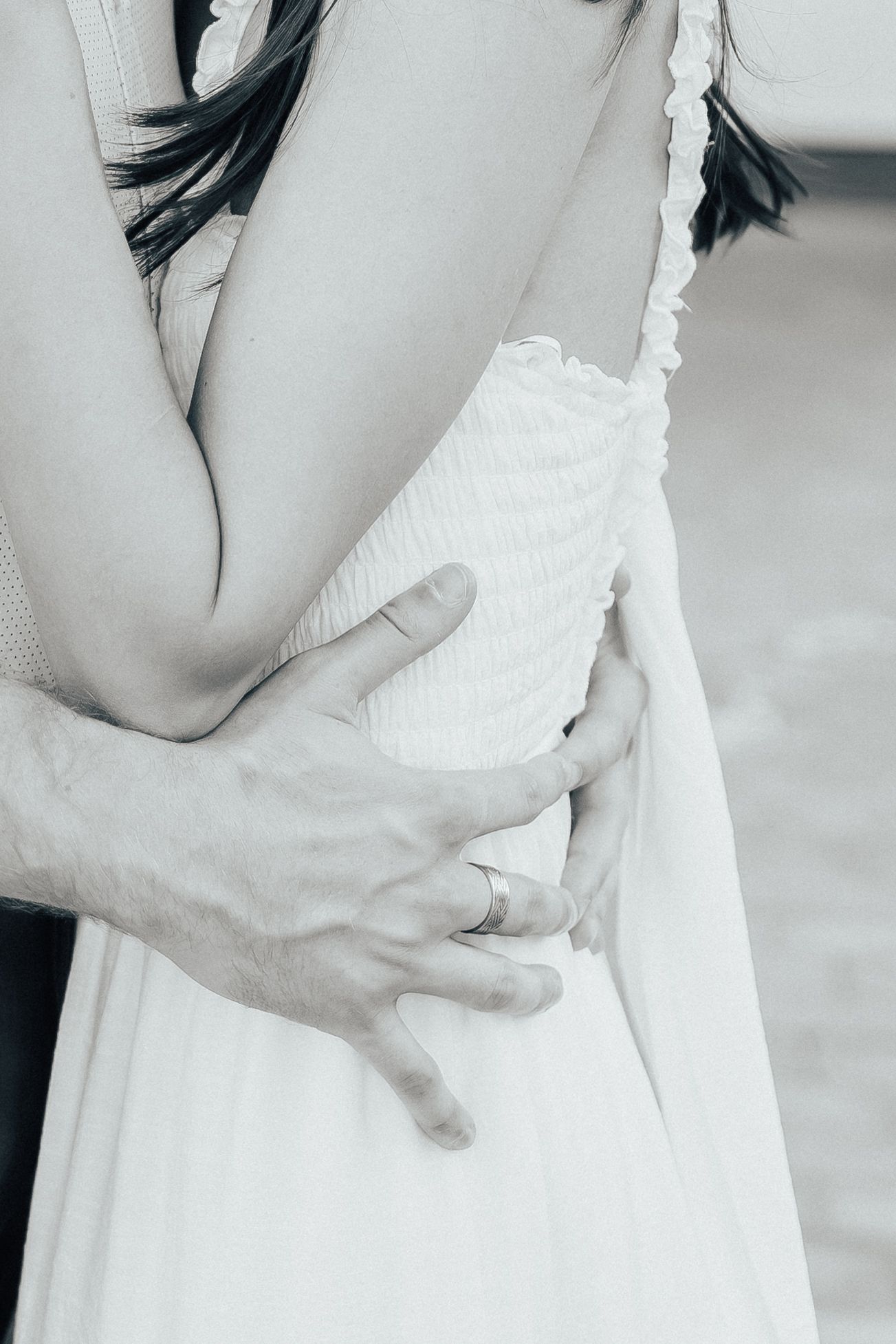 Close-up of white ruffled dress details and gentle embrace.