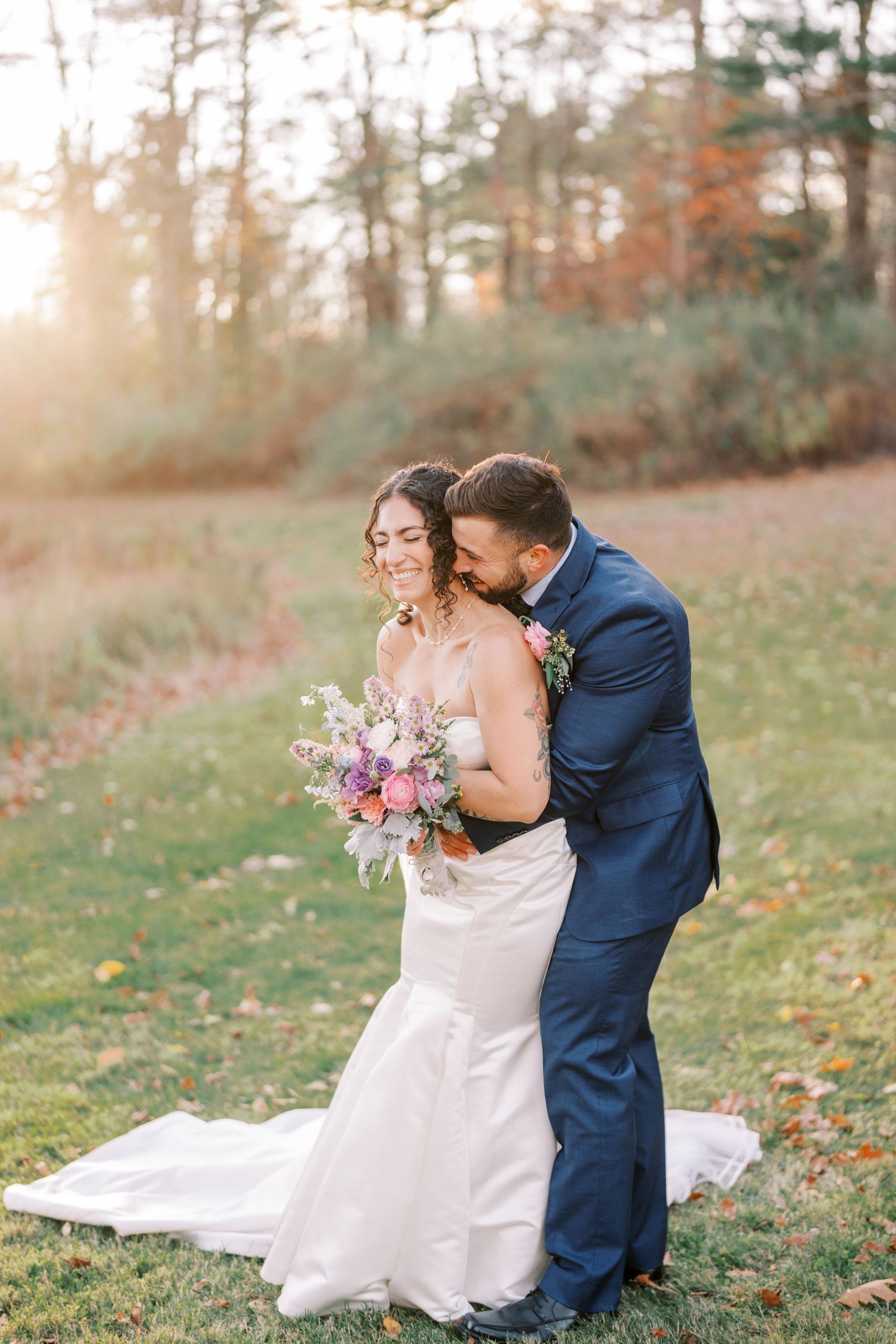 A romantic wedding couple shares intimate moments in an autumn field with fallen leaves at sunset.