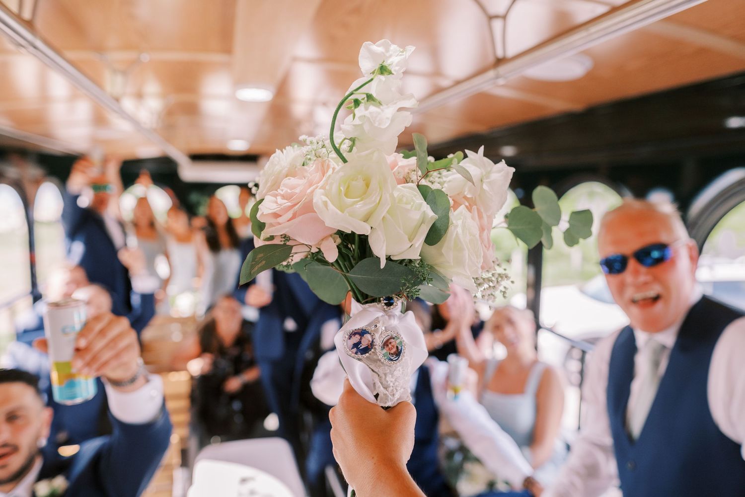 A delicate floral arrangement of pink and white blooms is held up during a celebratory moment on a party bus.