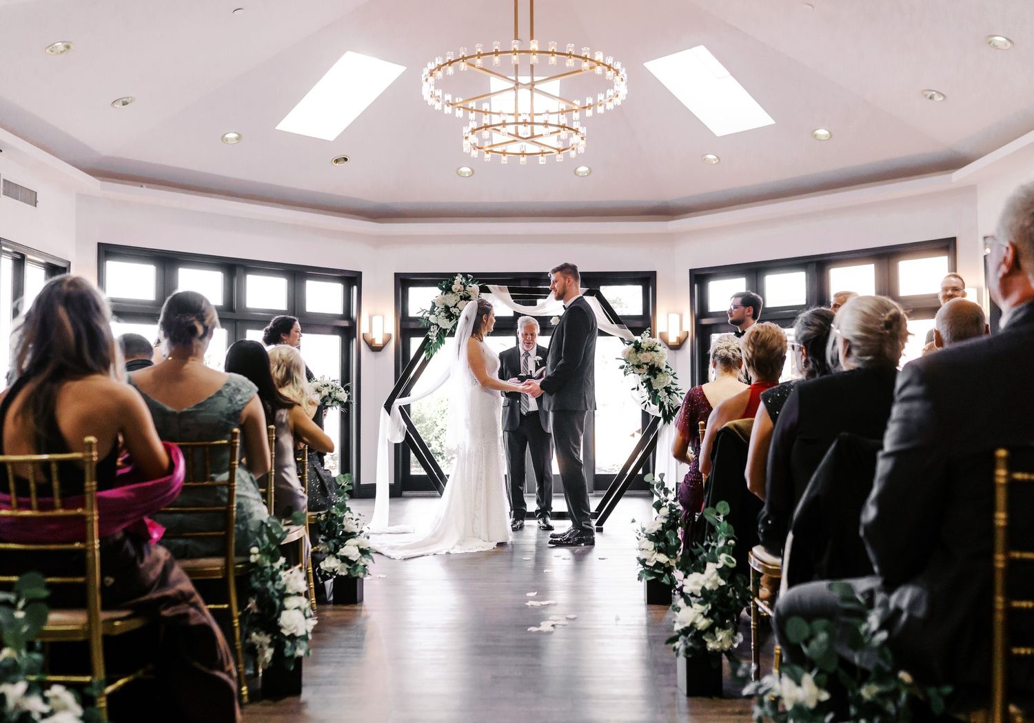 Multiple panoramic views of a spacious event hall with white decor, floral arrangements, and natural lighting.