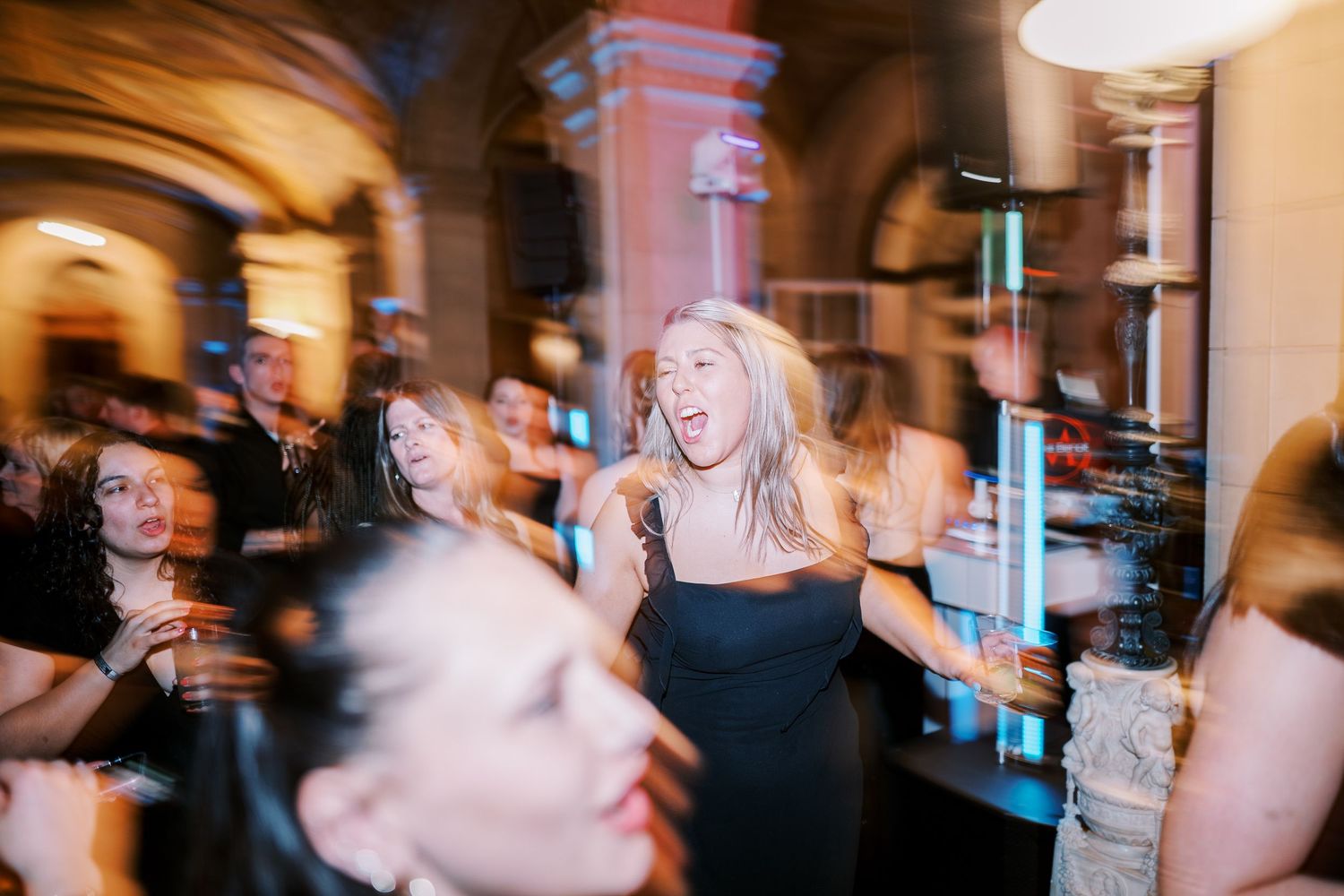 Wedding guests dancing and celebrating on a dimly lit dance floor at an elegant reception venue.