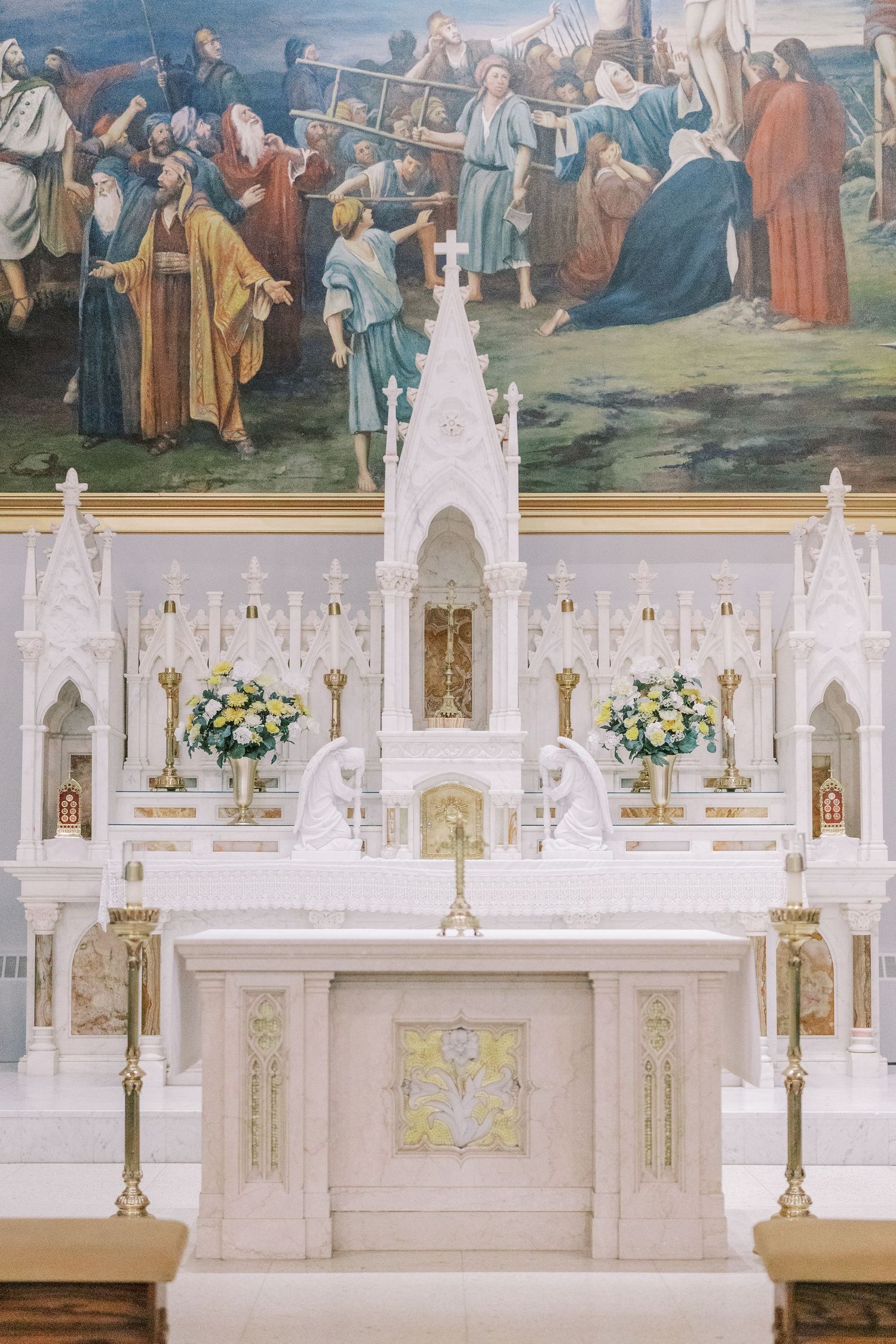 An ornate white cathedral altar decorated with floral arrangements and religious artwork.