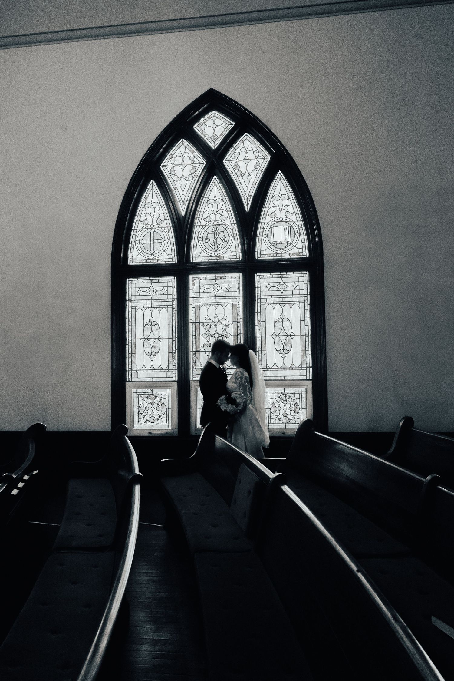 Dramatic black and white church interior with gothic stained glass windows.