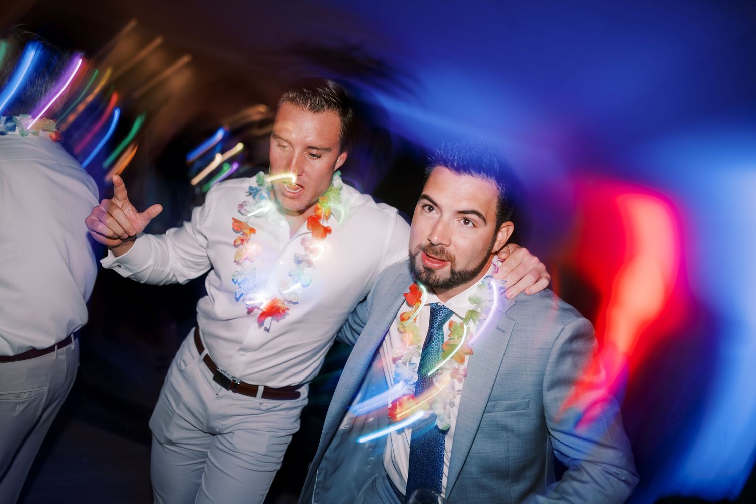 People celebrating at a nightclub with colorful lights and party decorations in a festive atmosphere.