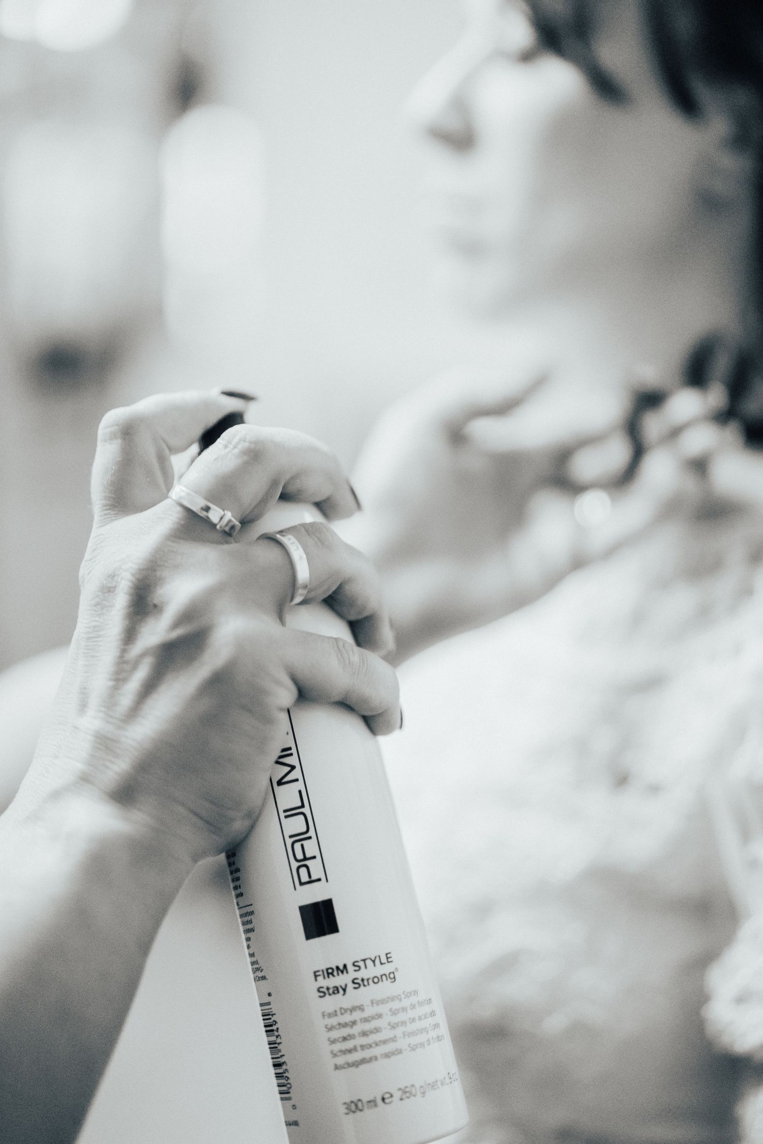 Close-up black and white shot of hands holding hair styling product bottle.