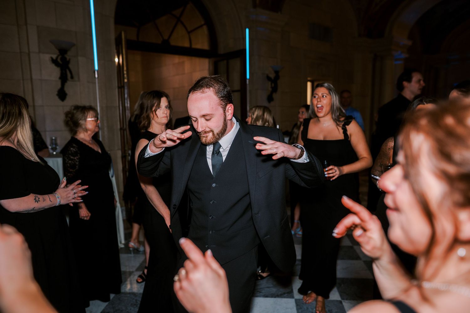 Guests celebrate with applause and laughter during a joyful moment at an indoor wedding ceremony.