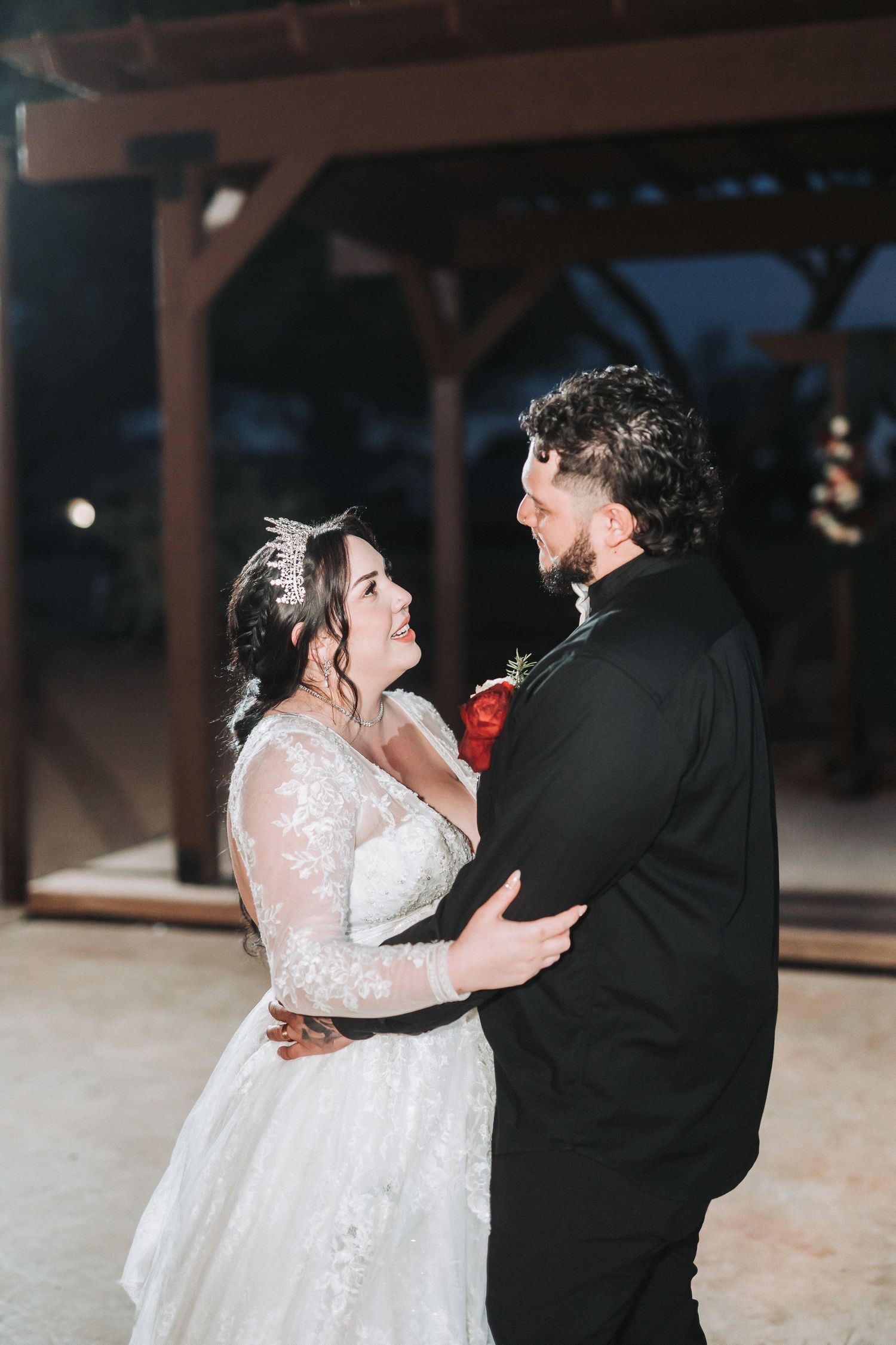 A couple shares an intimate moment in formal wedding attire during their evening wedding celebration.