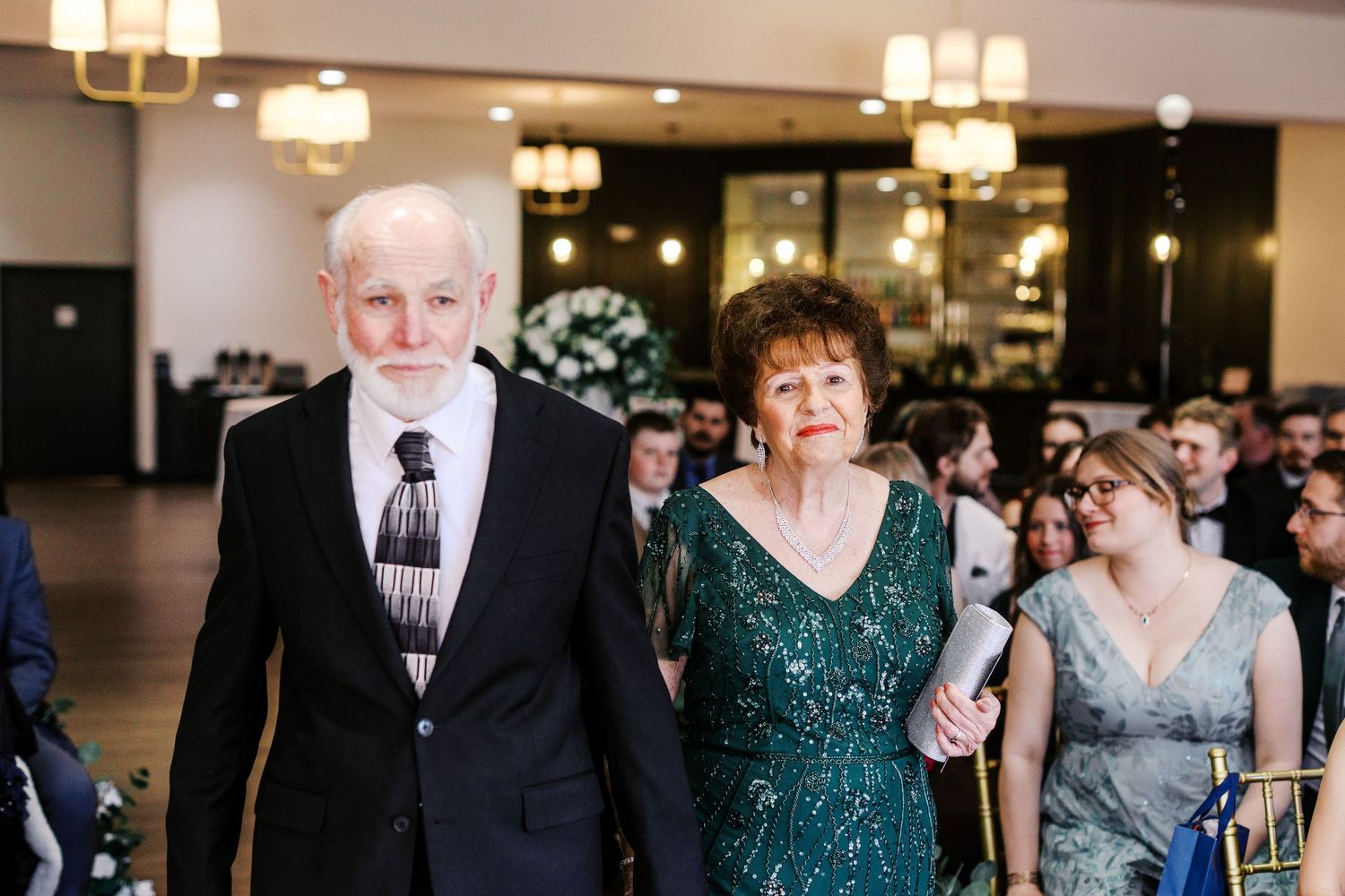 Wedding guests gathered in formal attire during an indoor reception celebration.