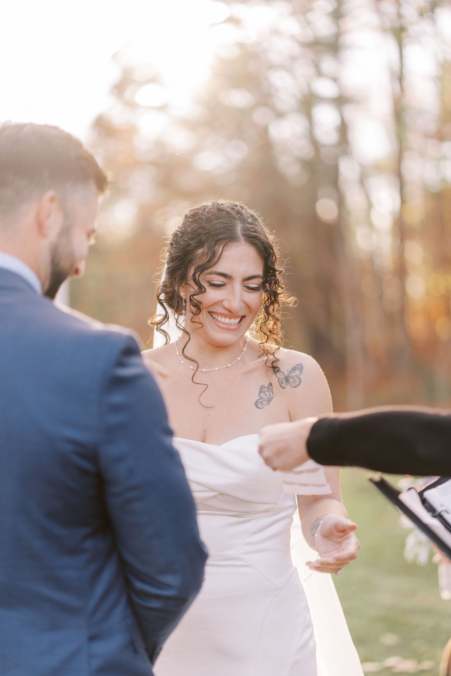 A couple shares an intimate moment during their autumn wedding ceremony outdoors with golden sunlight filtering through trees.