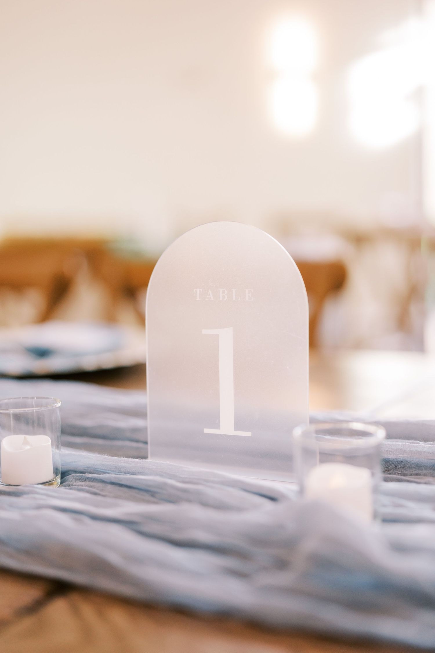 A frosted glass number one marker sits on a blurred gray surface with soft bokeh lighting in the background.