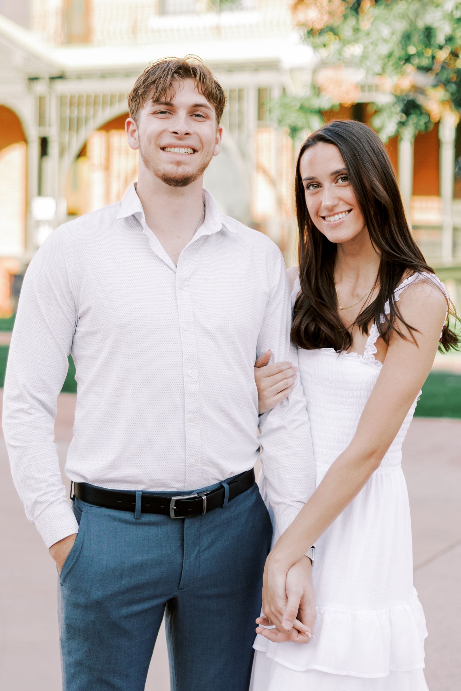Romantic couple in white and blue outfits sharing playful moments together outdoors.