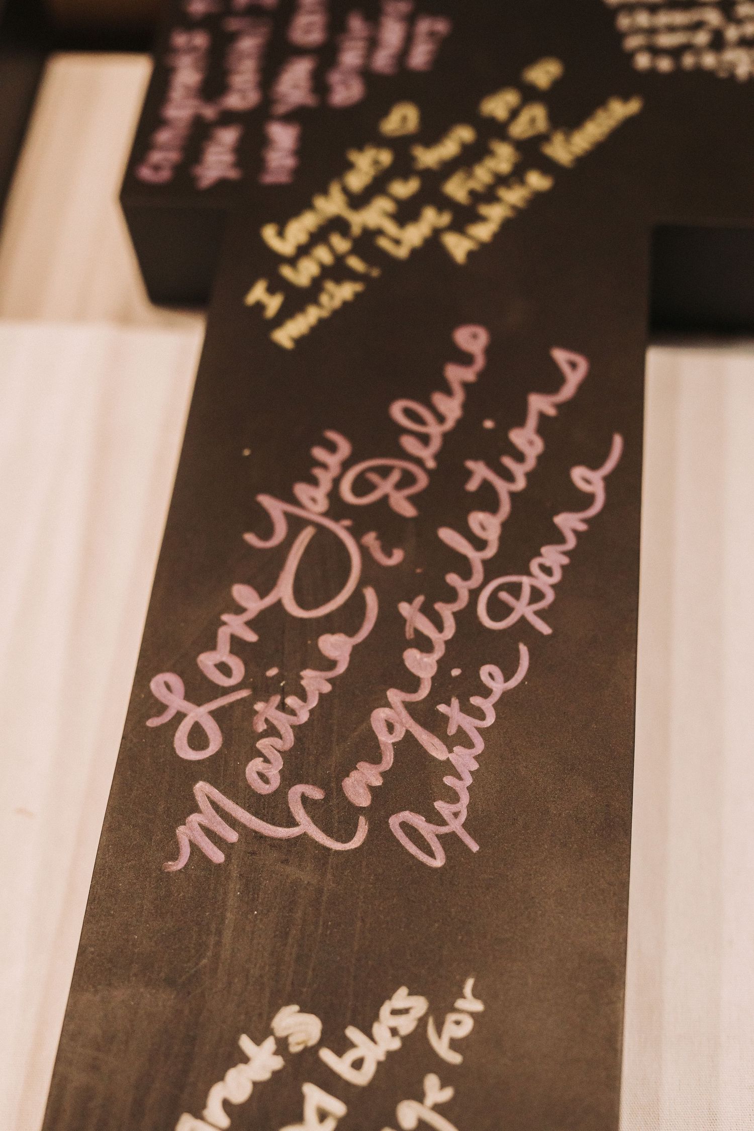 Handwritten pink text messages written on a dark wooden surface in a vintage-style photograph.