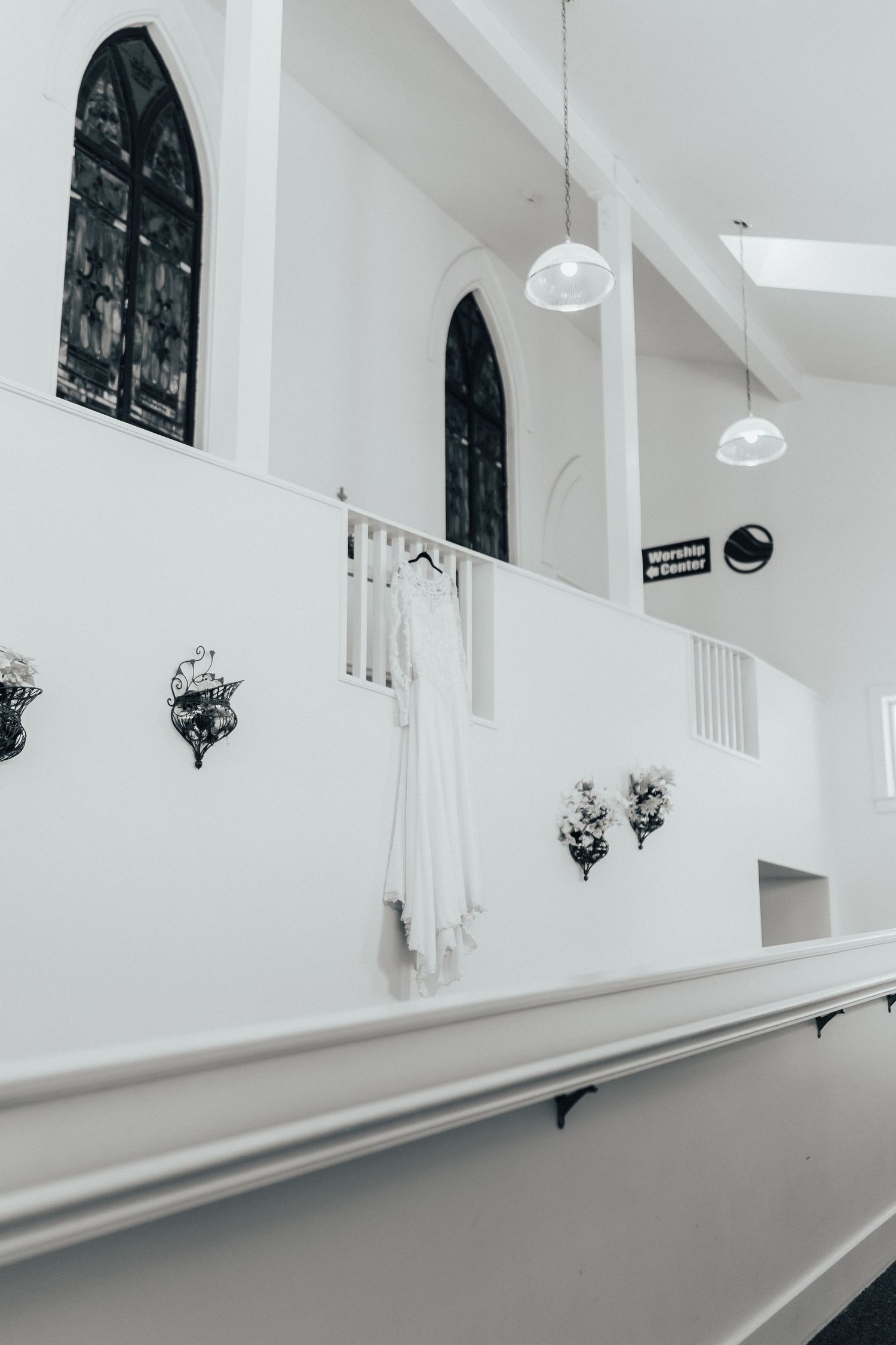 White church interior with arched windows, pendant lights and decorative wall sconces.