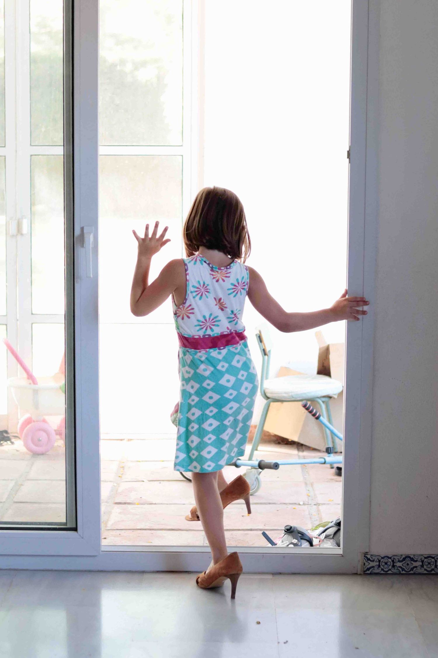 Person reaching for door handle while wearing floral top and patterned turquoise skirt.
