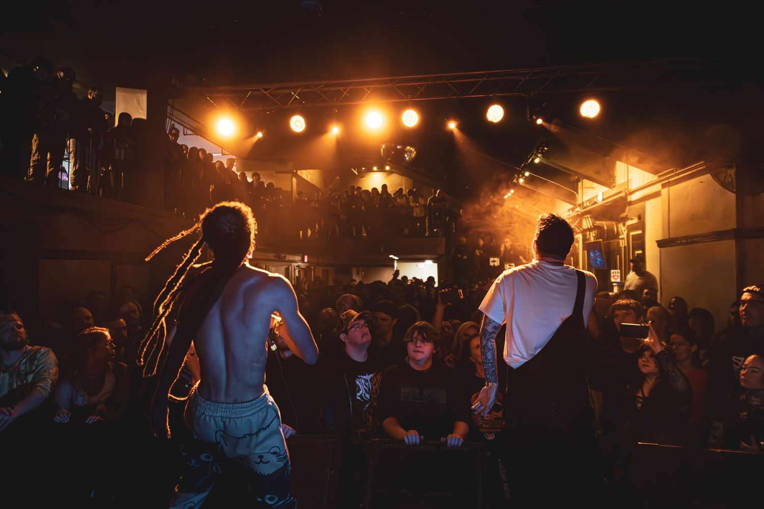 Concert venue with warm amber lighting and silhouetted crowd.
