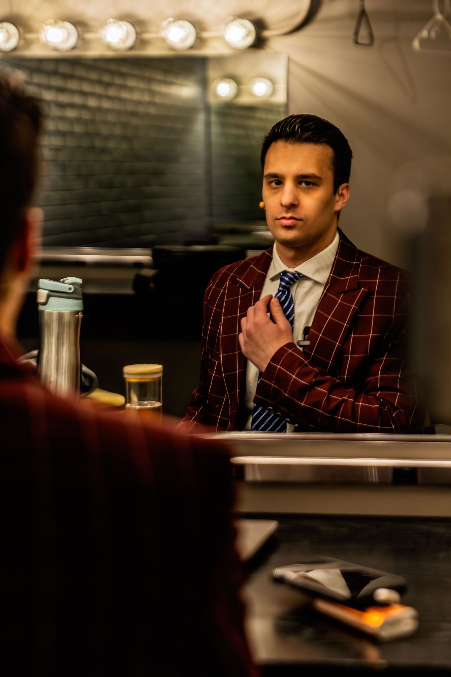 Professional wearing a burgundy pinstripe suit sitting in a dimly lit venue.