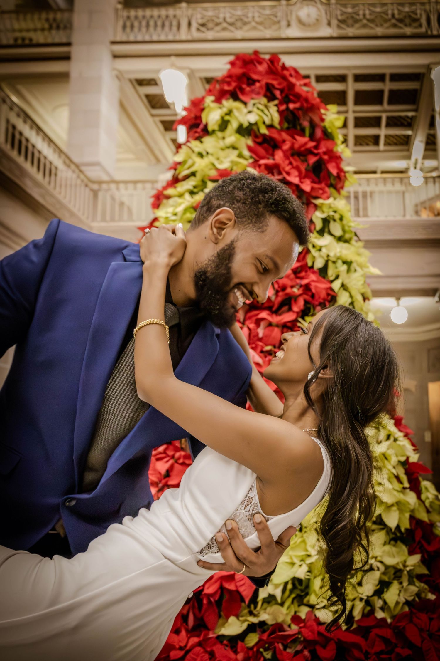 Husband and wife staring at each other in front of a Christmas tree.