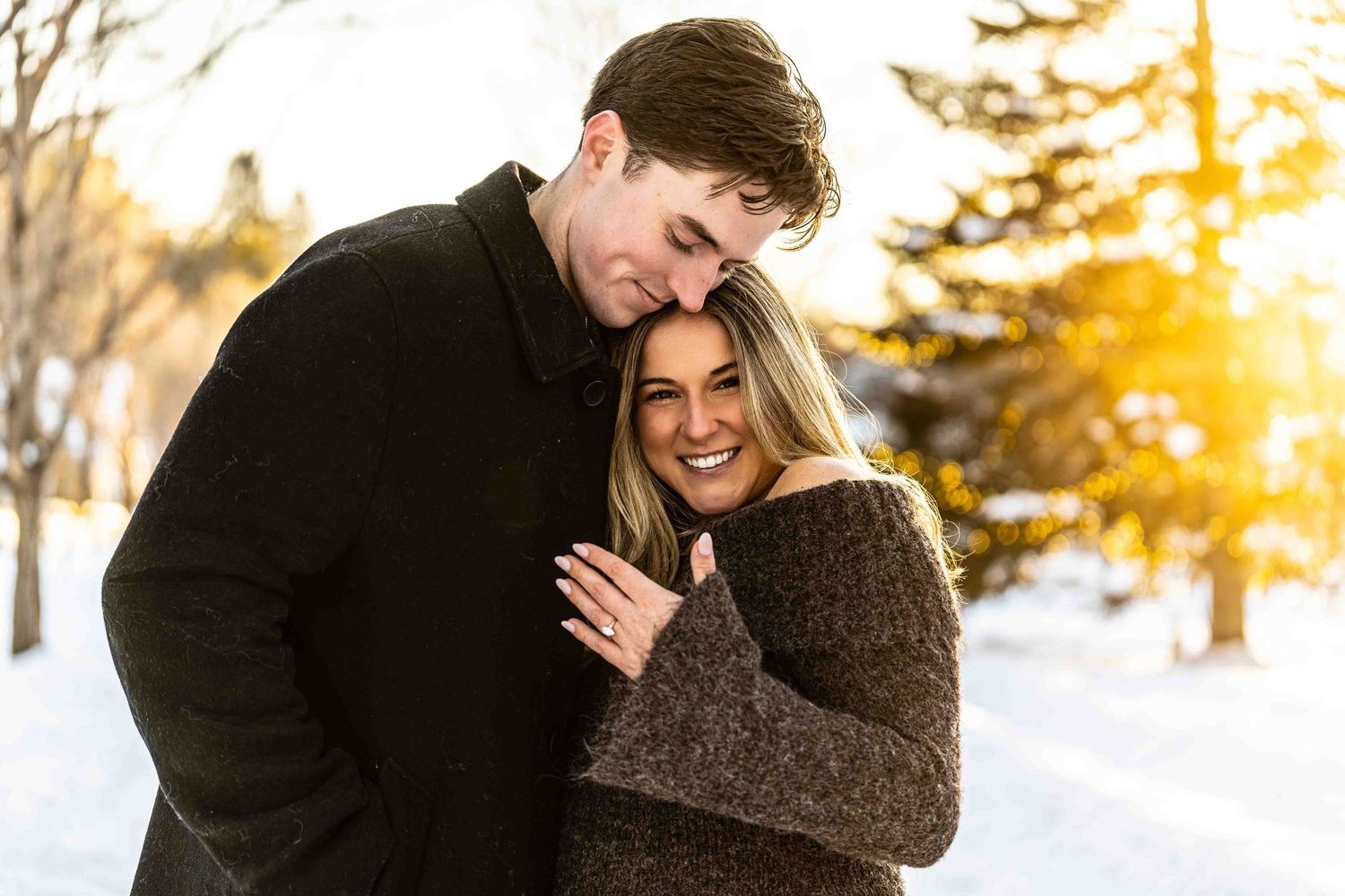 Couple sharing intimate moments during a golden sunset photoshoot in winter landscape.