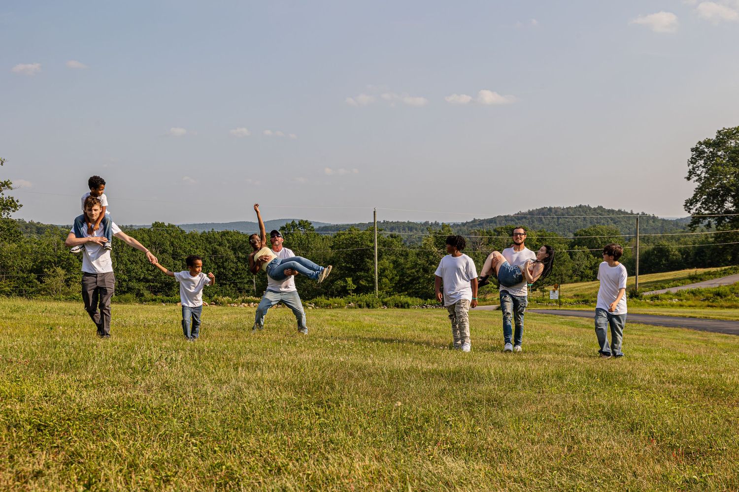 Group photo session taking place in a scenic grassy field on a sunny day.