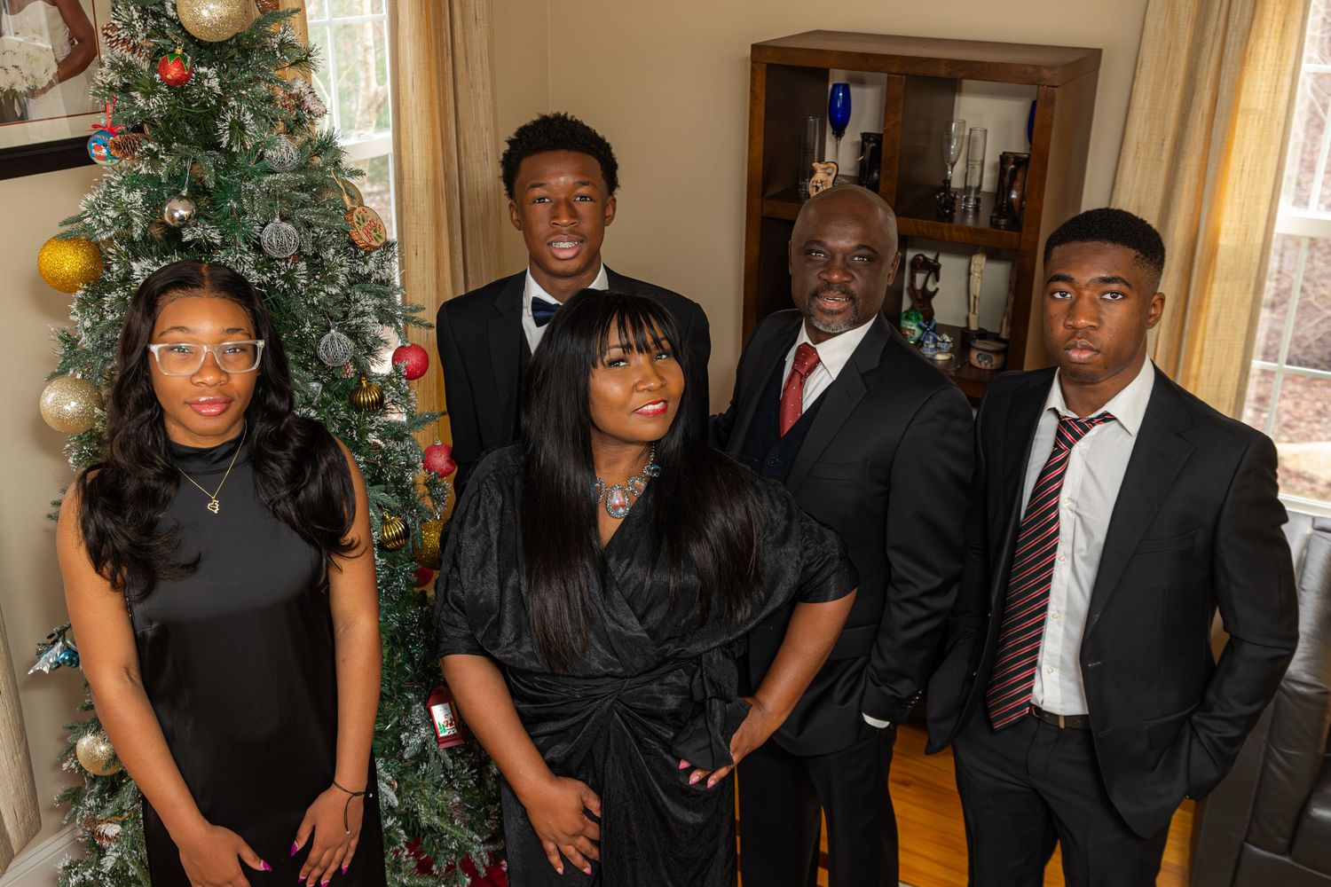 Formal holiday gathering with Christmas tree decorations in a well-lit room.