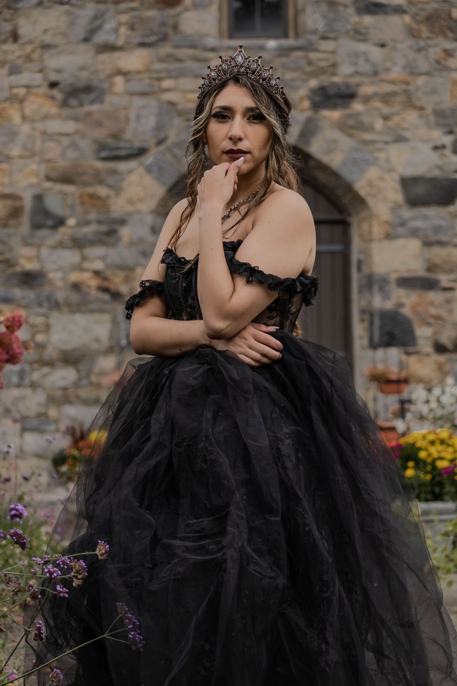 Dramatic photoshoot featuring a black tulle ballgown against a stone wall backdrop.