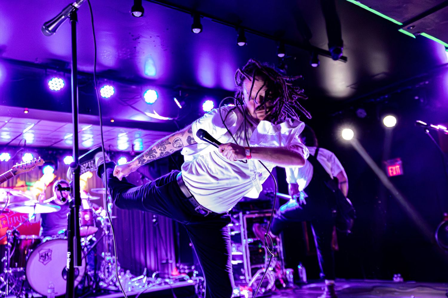 Concert venue illuminated with vibrant purple stage lighting and atmospheric effects.