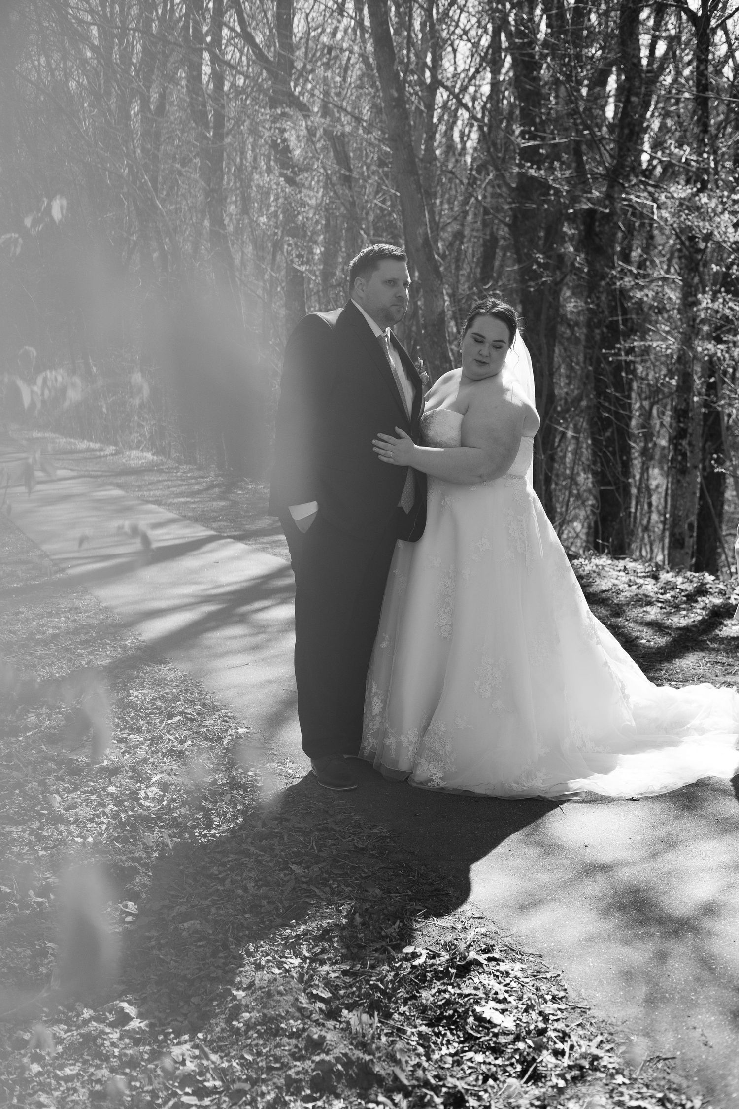 A couple shares an intimate dance in the sunlit woods, her flowing white wedding dress swaying among autumn leaves.