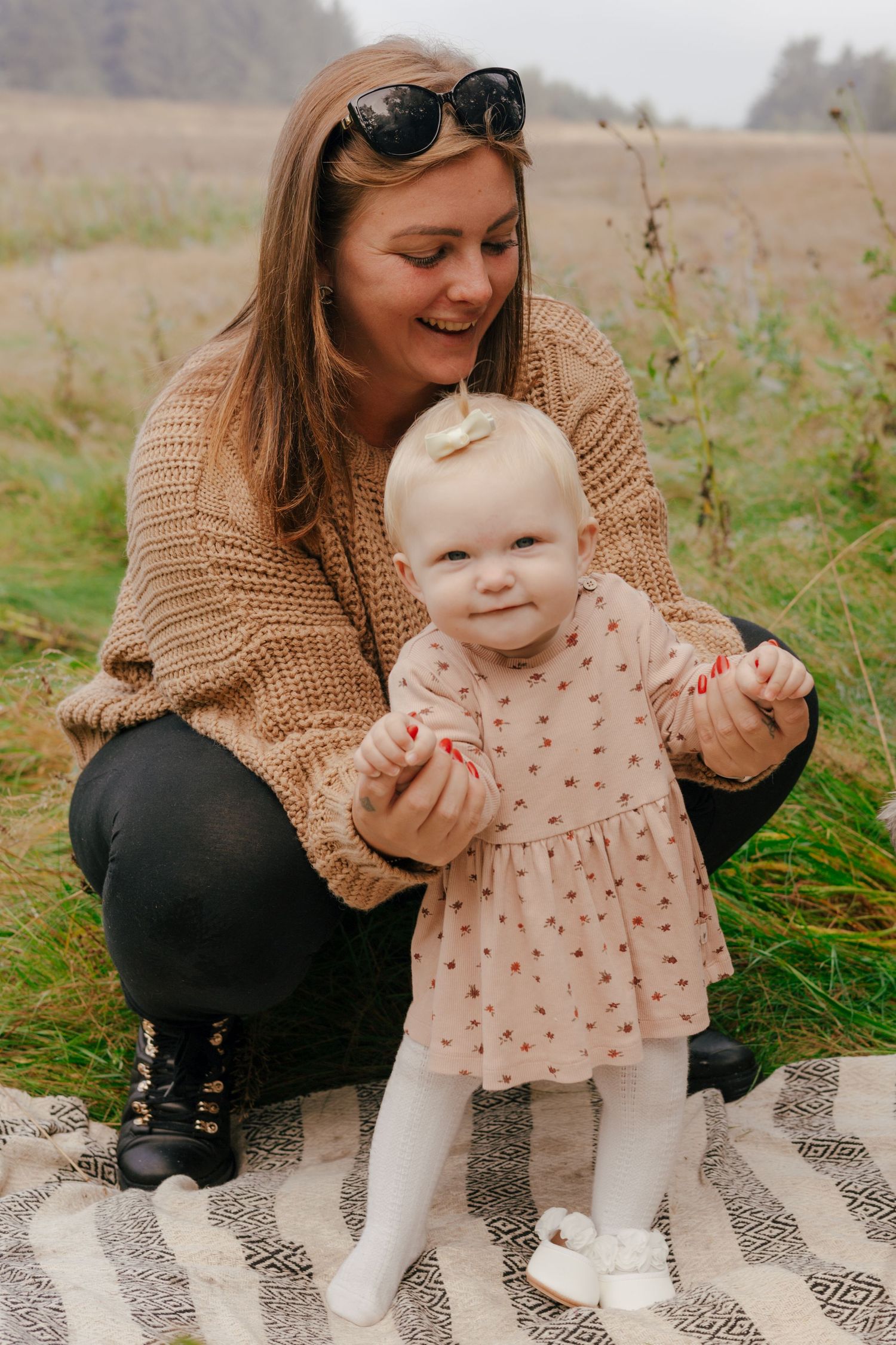A joyful outdoor moment on a blanket in a natural field setting.
