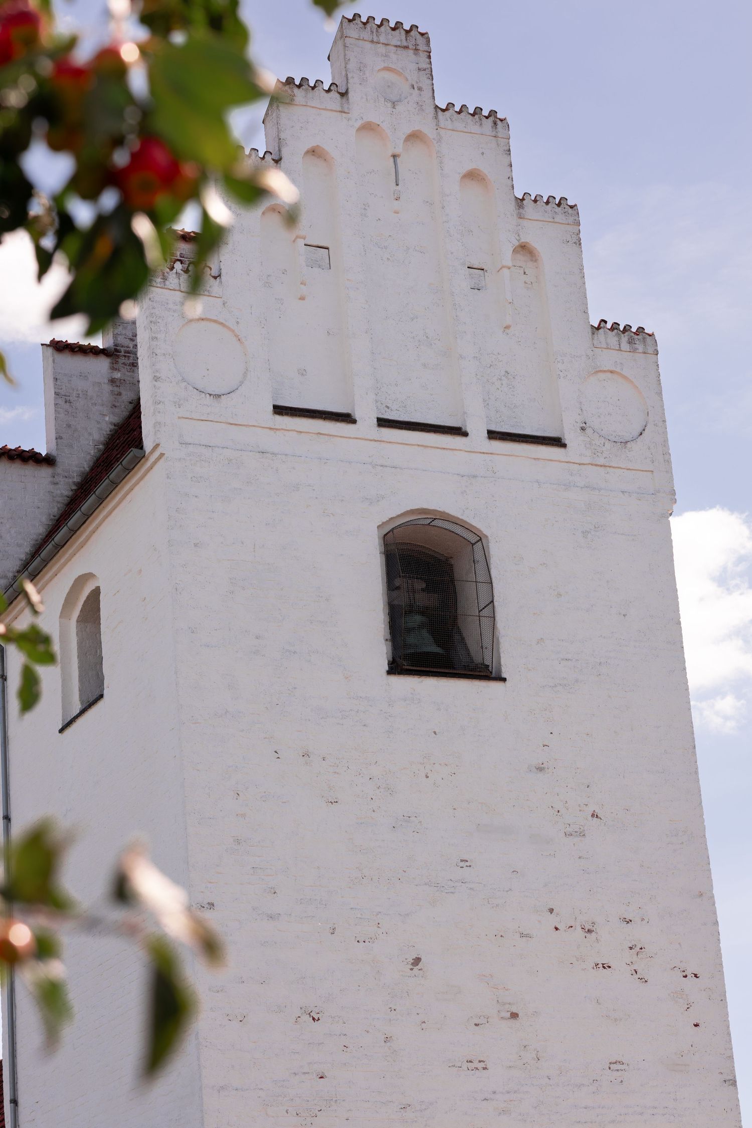 Ornate white church facade with stepped gables and gothic architectural details against a bright sky.