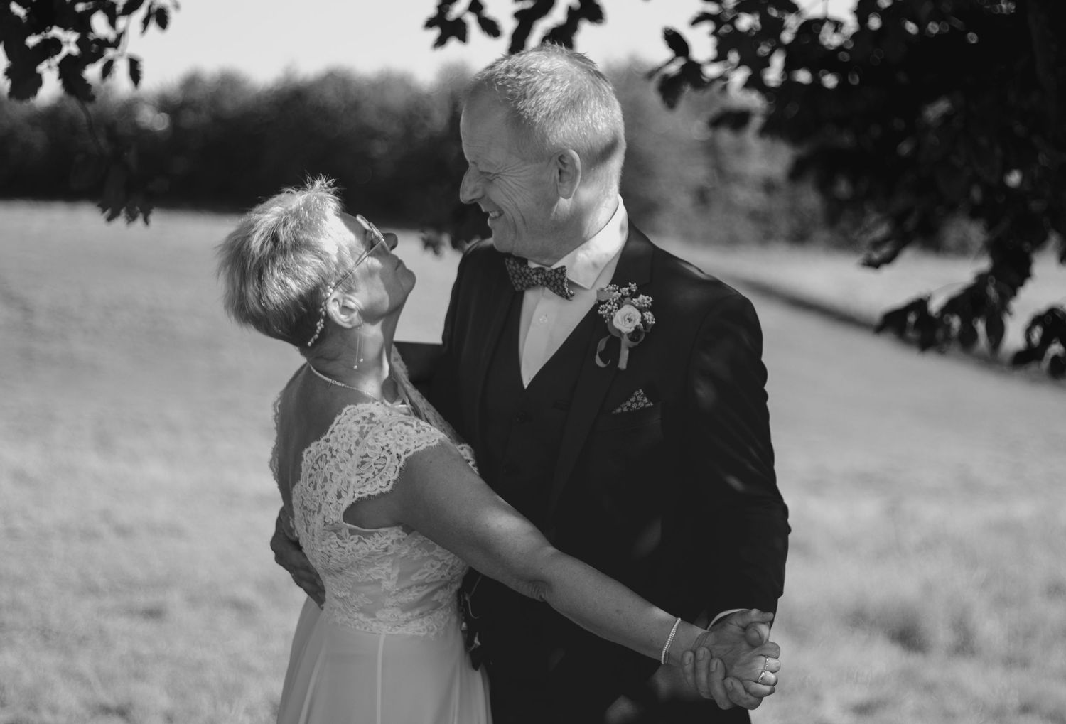 Romantic black and white photo of a couple dancing outdoors in formal wedding attire.